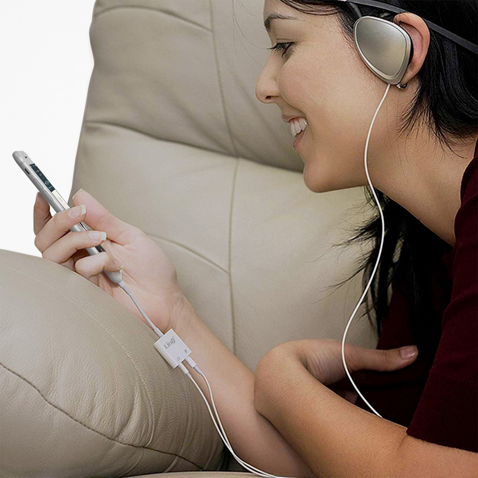 Frau, die Musik mit Kopfhörern hört. Sie hält ein Telefon, das mit einem Audioadapter verbunden ist.