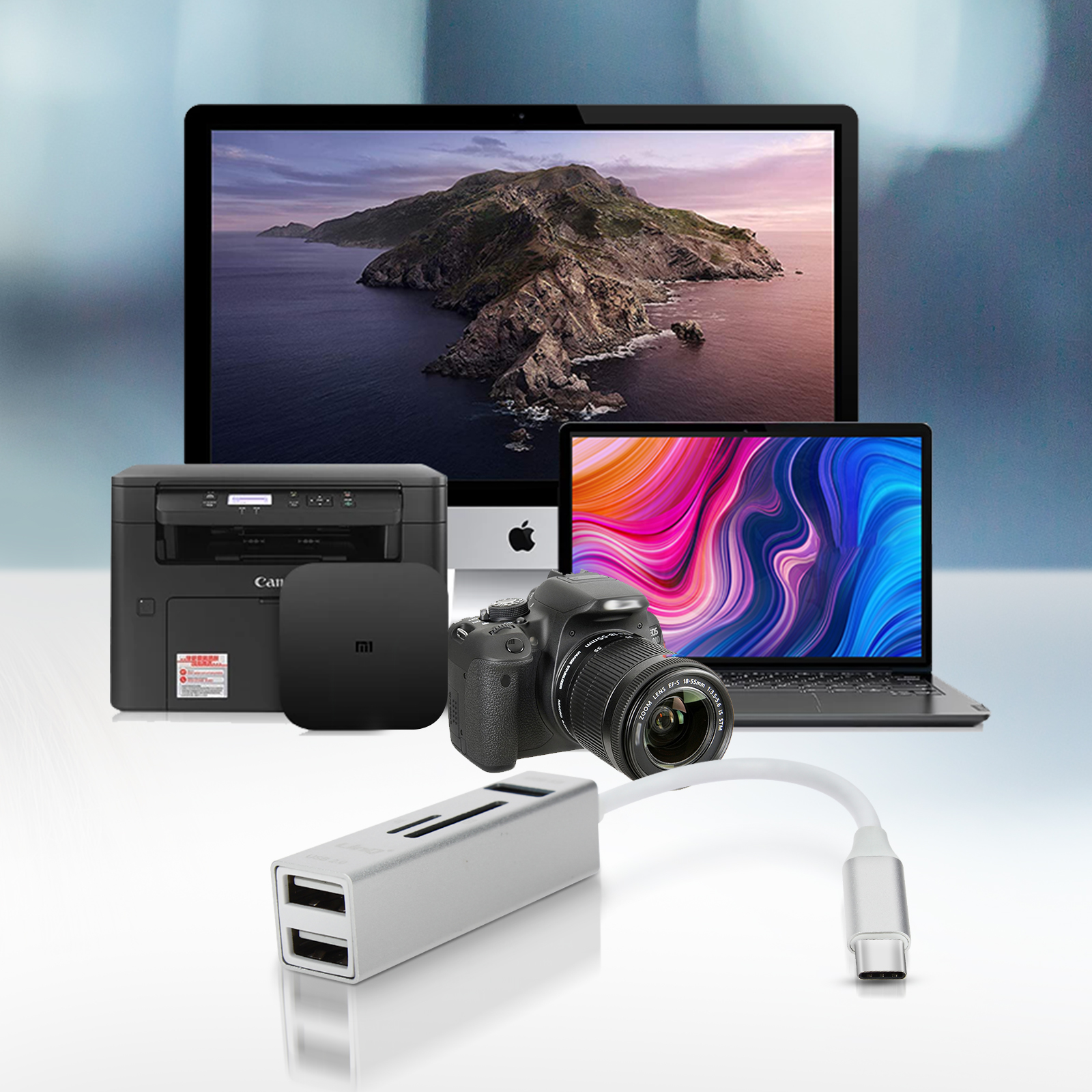 Una collezione di gadget tecnologici: monitor, laptop, stampante, fotocamera e adattatore USB.