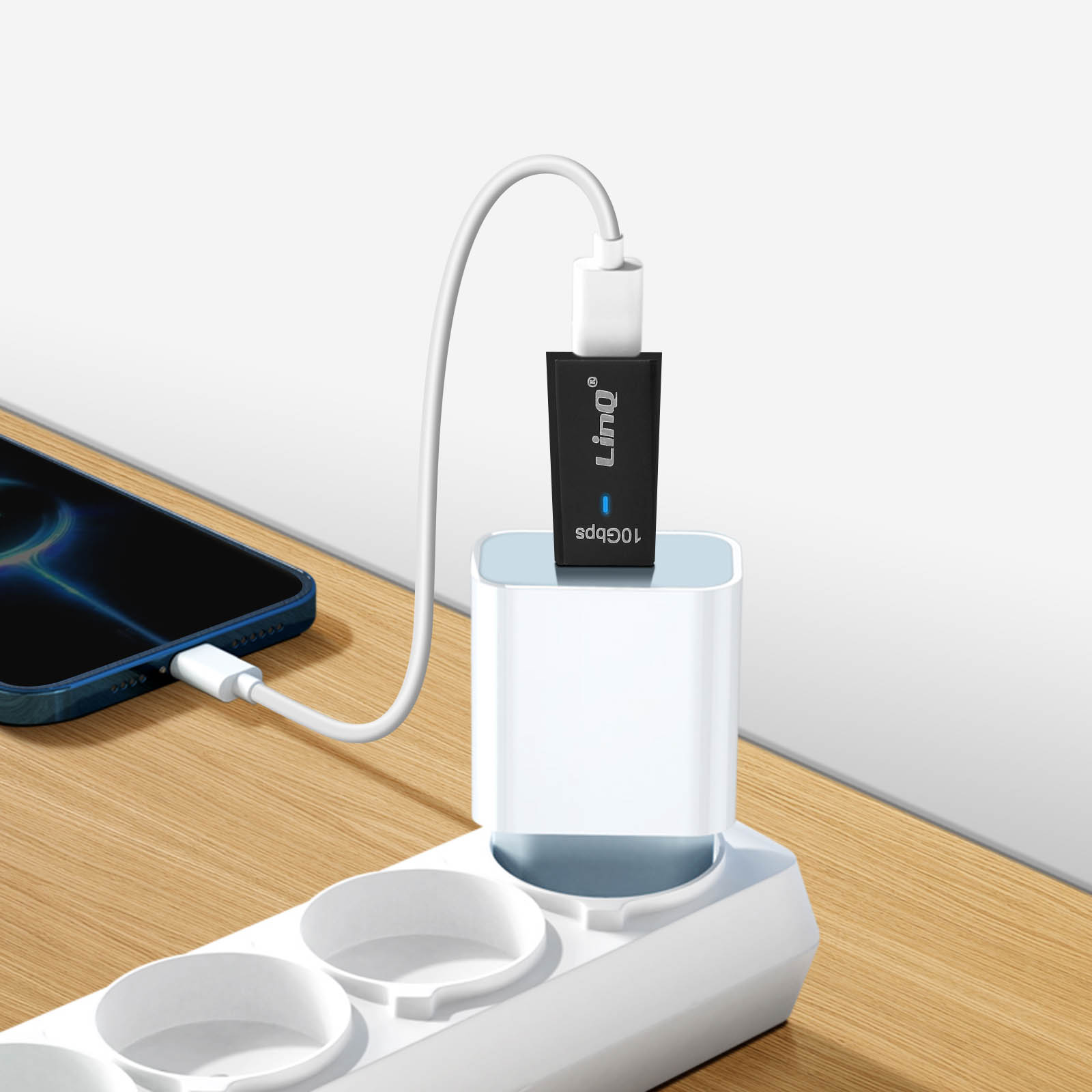 Adattatore USB-C collegato a una presa multipla. Telefono connesso. Superficie in legno.