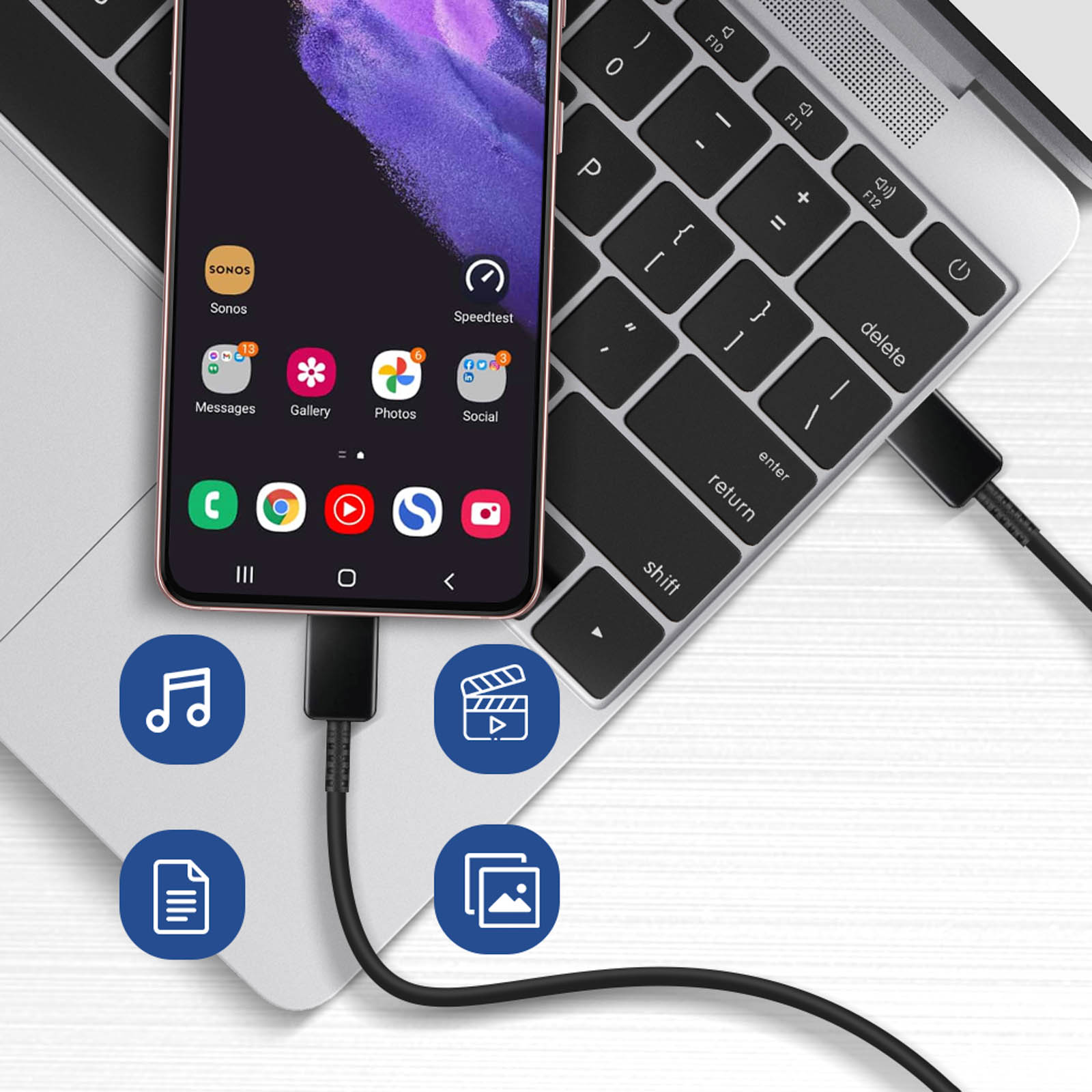 Smartphone collegato a laptop con cavo nero, icone app. Sfondo sfocato.