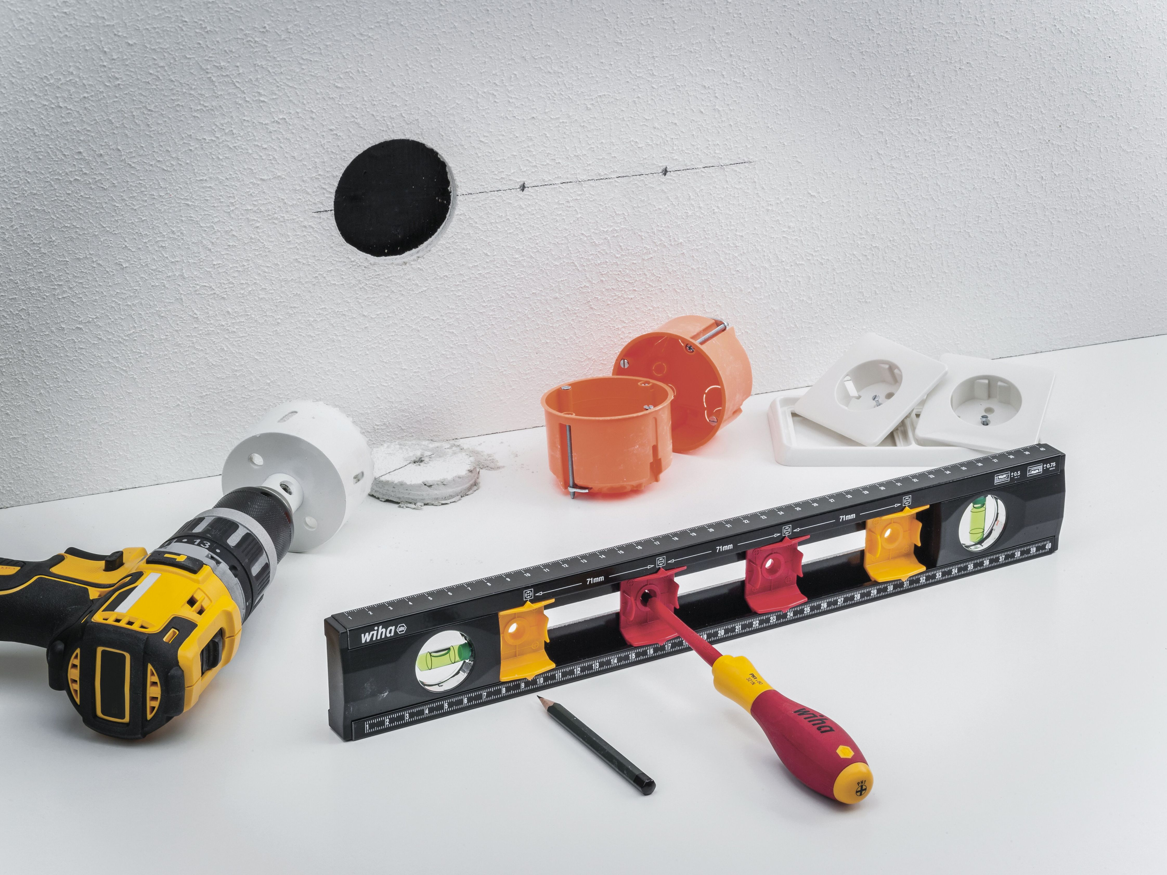 Werkzeuge für Elektroarbeiten, einschließlich Bohrer, orangefarbene Dosen und Wasserwaage.
