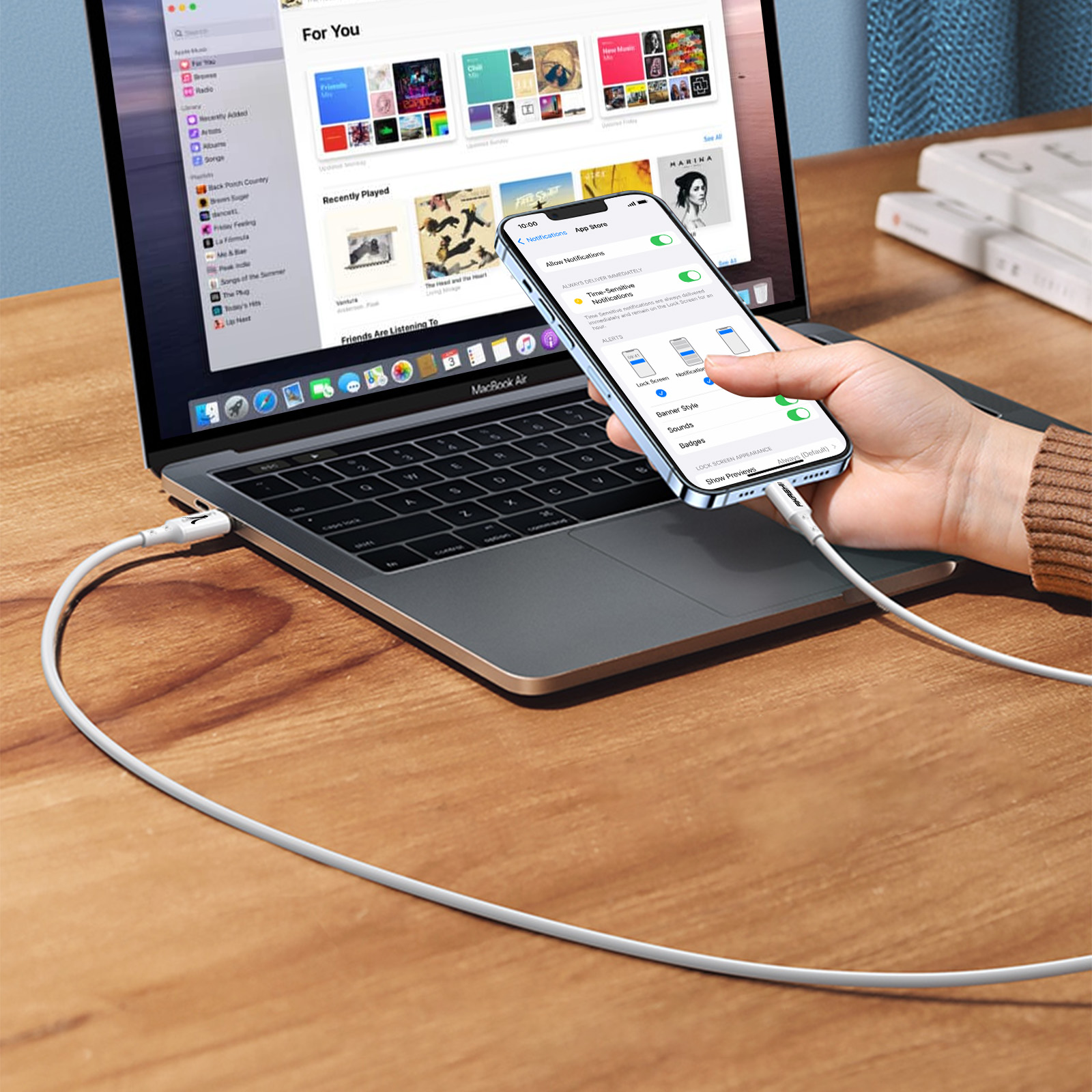 Eine Person verwendet ein Telefon, das mit einem Laptop mit weißem Kabel verbunden ist.