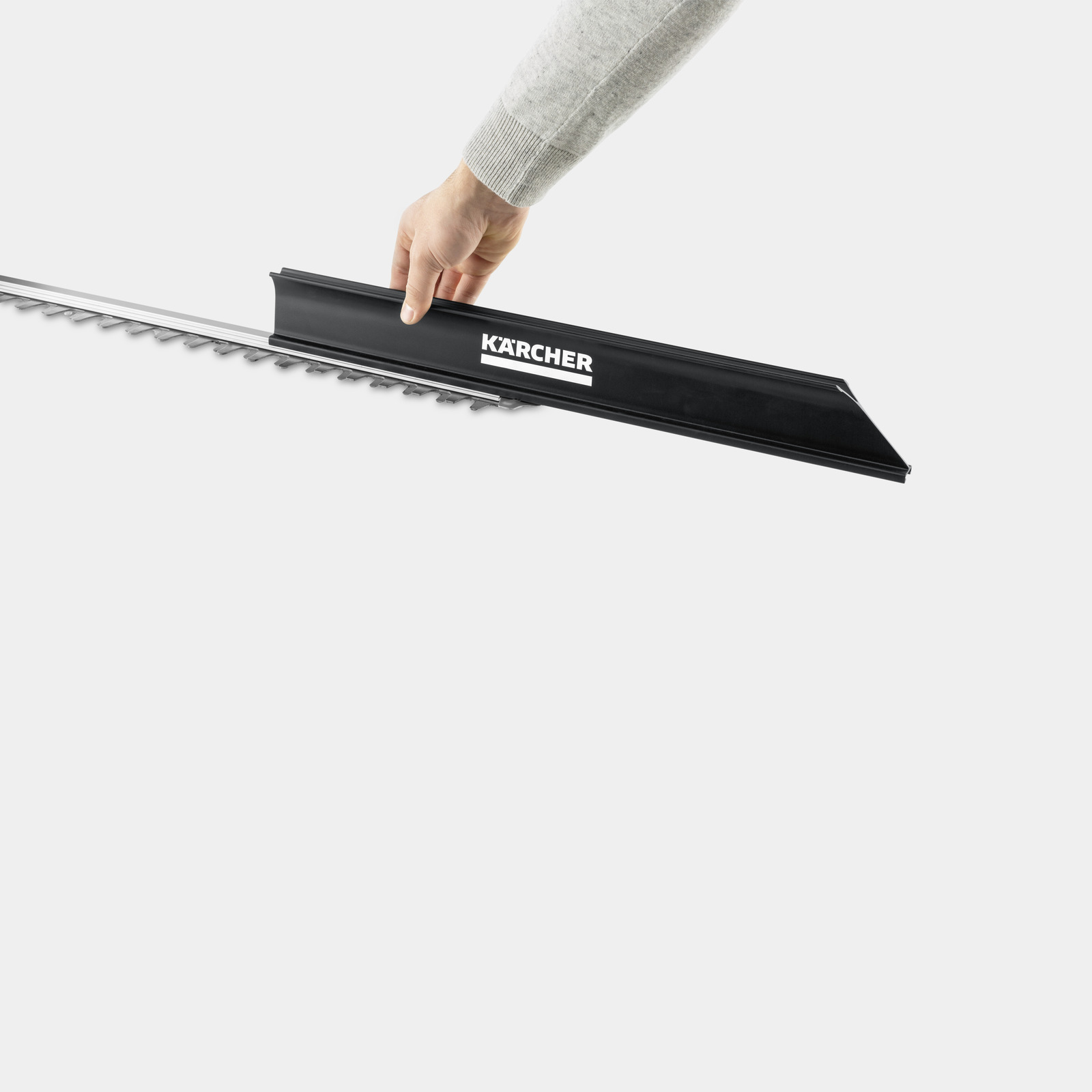 Osoba trzymająca czarną podkaszarkę Kärcher nad ostrzami trymera.