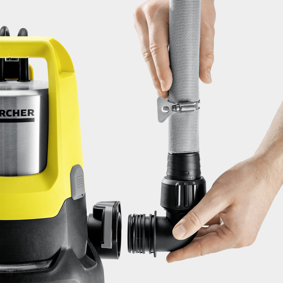 Osoba podłączająca czarny wąż do żółto-czarnej pompy wodnej. Ujęcie z bliska.