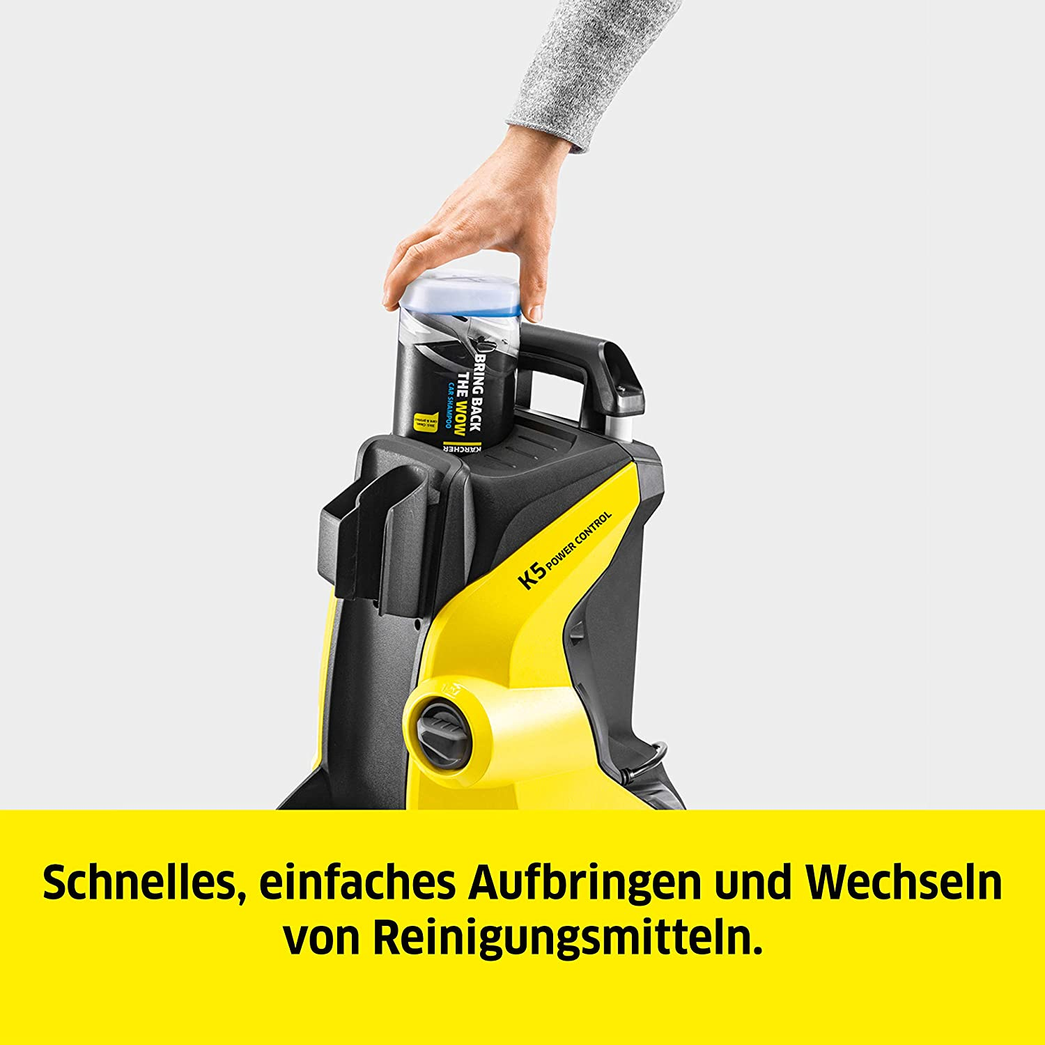 Hand legt eine Reinigungsflasche auf einen schwarz-gelben Hochdruckreiniger.