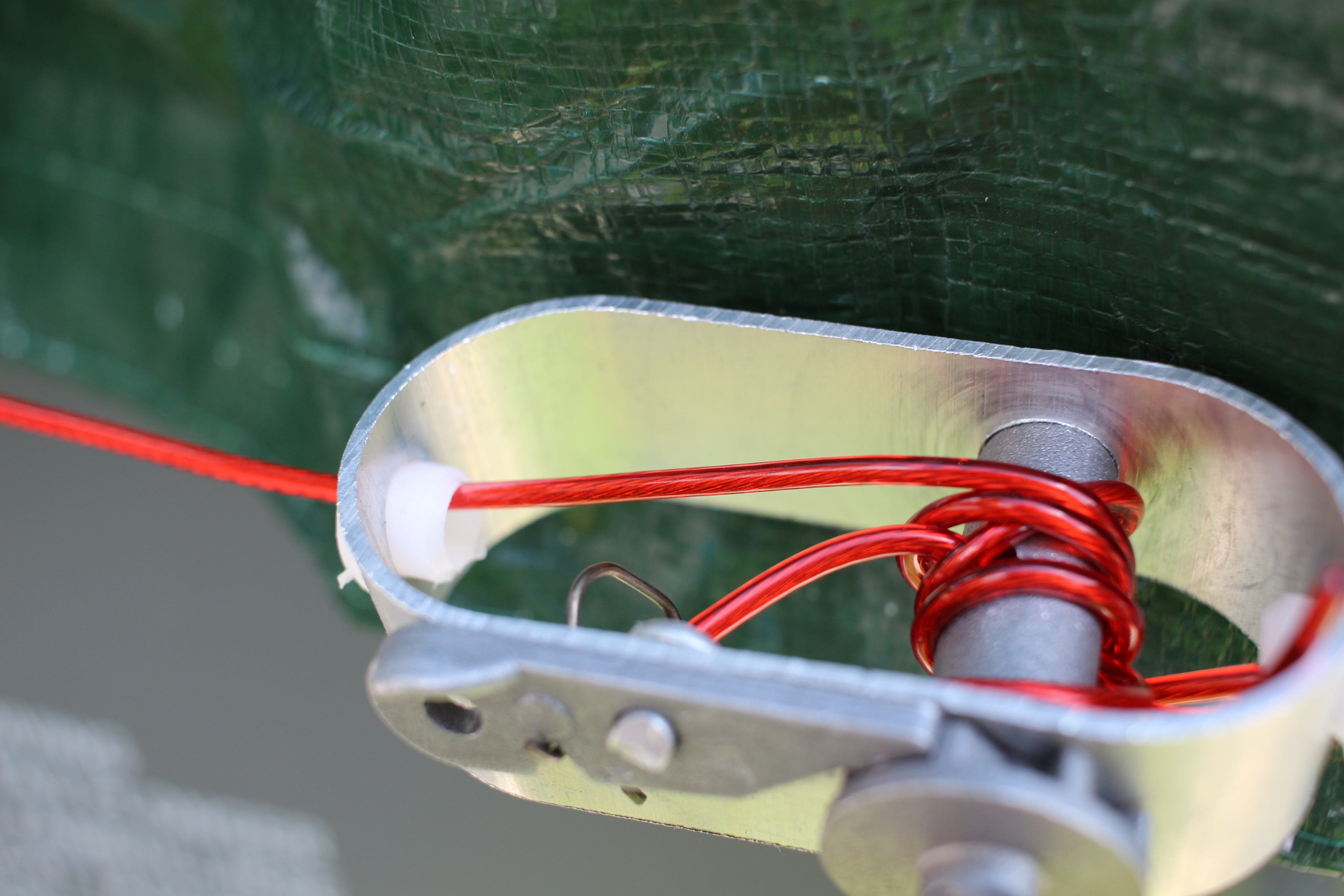 Nahaufnahme eines Aluminiumgeräts mit rotem Seil, zum Sichern einer Plane.