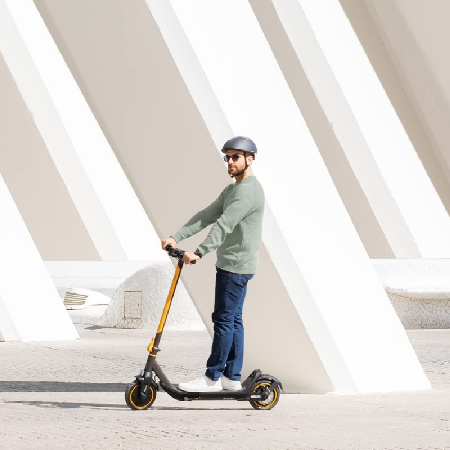 Uomo che guida uno scooter giallo e nero su uno sfondo bianco brillante con linee diagonali.