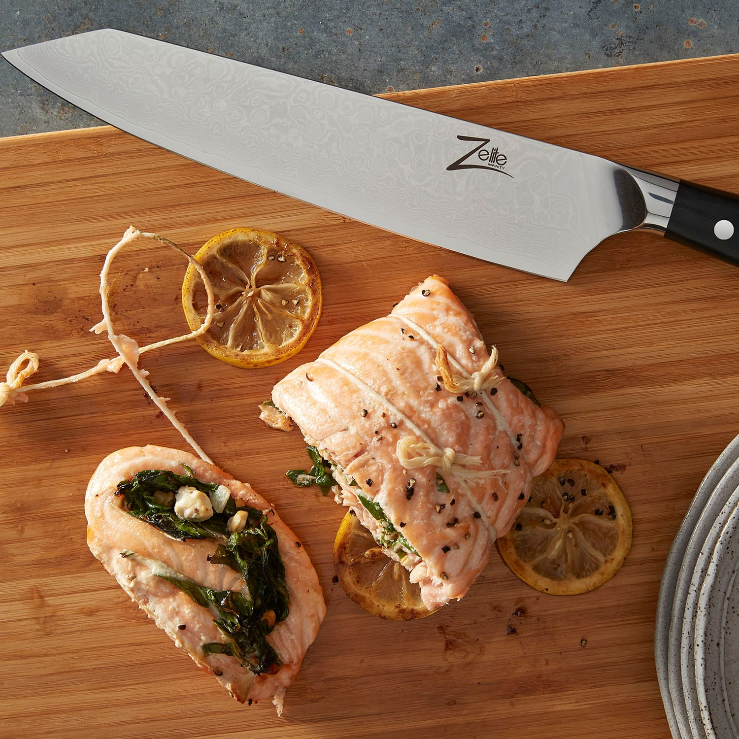 Gekochter Lachs mit Zitronenscheiben auf einem hölzernen Schneidebrett mit einem Messer.