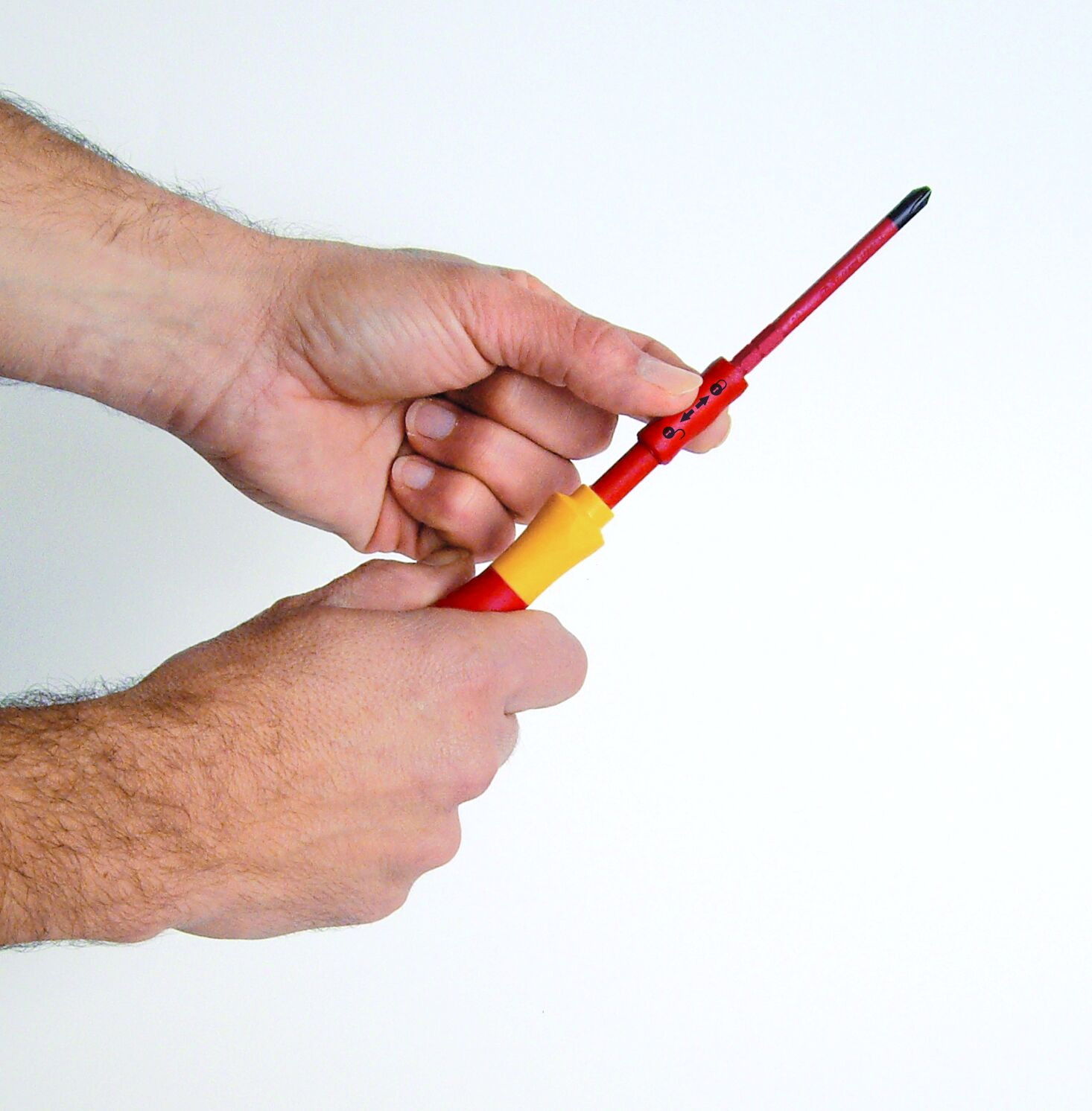 Dłonie trzymające czerwono-żółty śrubokręt na białym tle.