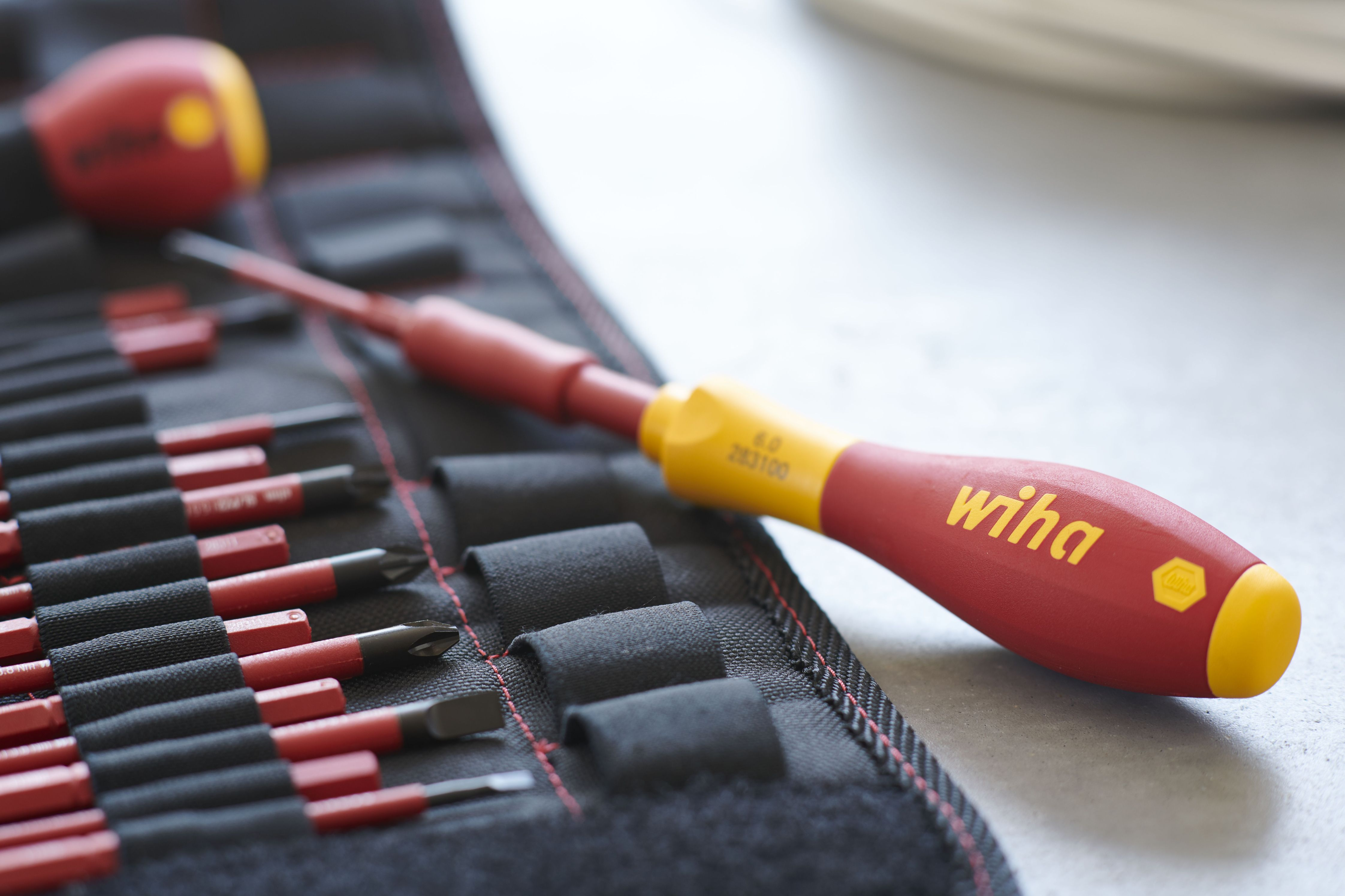 Czerwono-żółty śrubokręt umieszczony na rolce narzędziowej. Wiha jest nadrukowane na uchwycie.