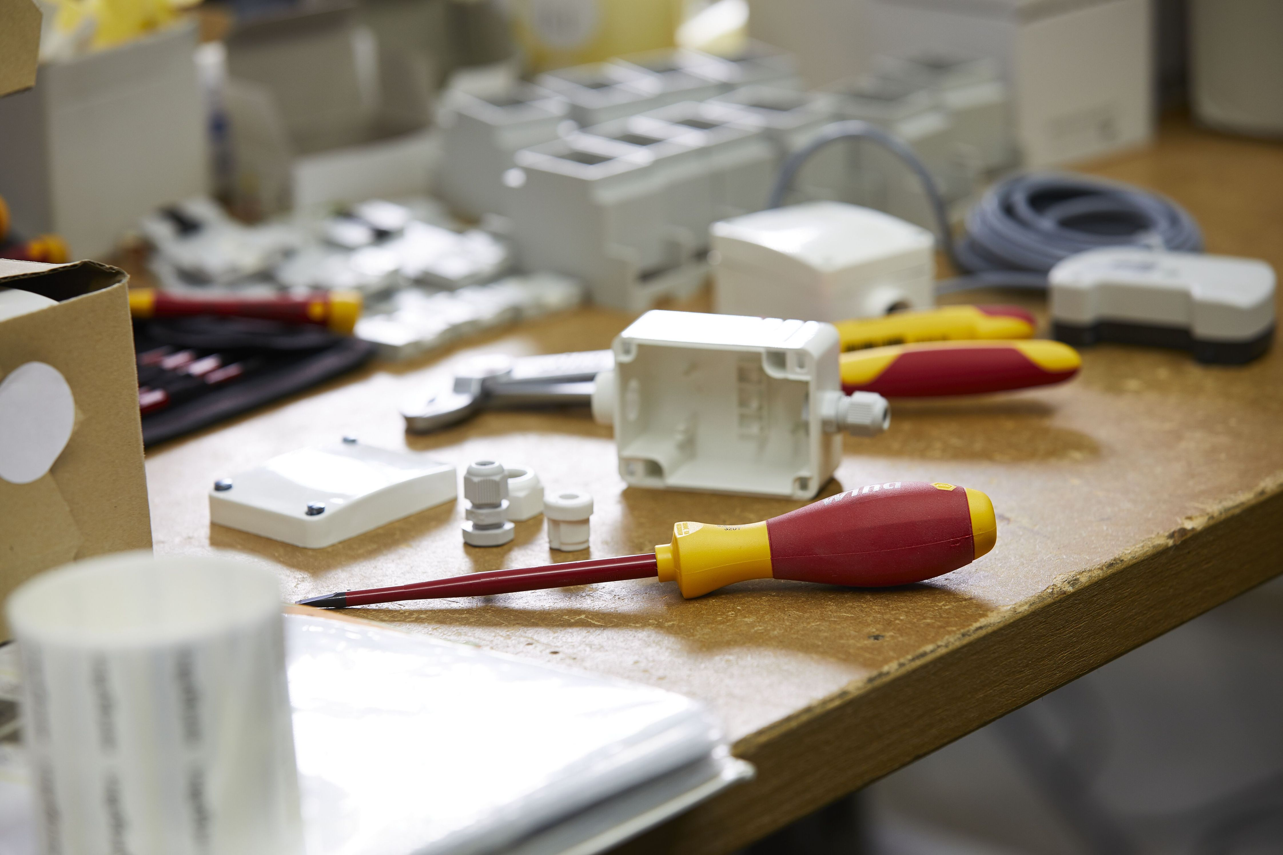 Warsztat z narzędziami, w tym śrubokrętem i elementami skrzynki elektrycznej.