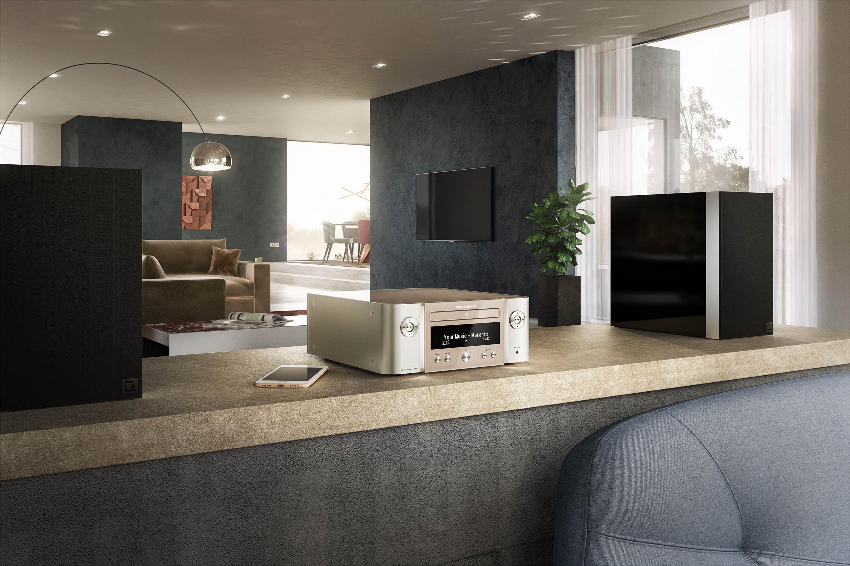 Modernes Wohnzimmer mit Soundsystem auf einer Theke. Ein Fernseher, Lautsprecher und ein Telefon sind sichtbar.