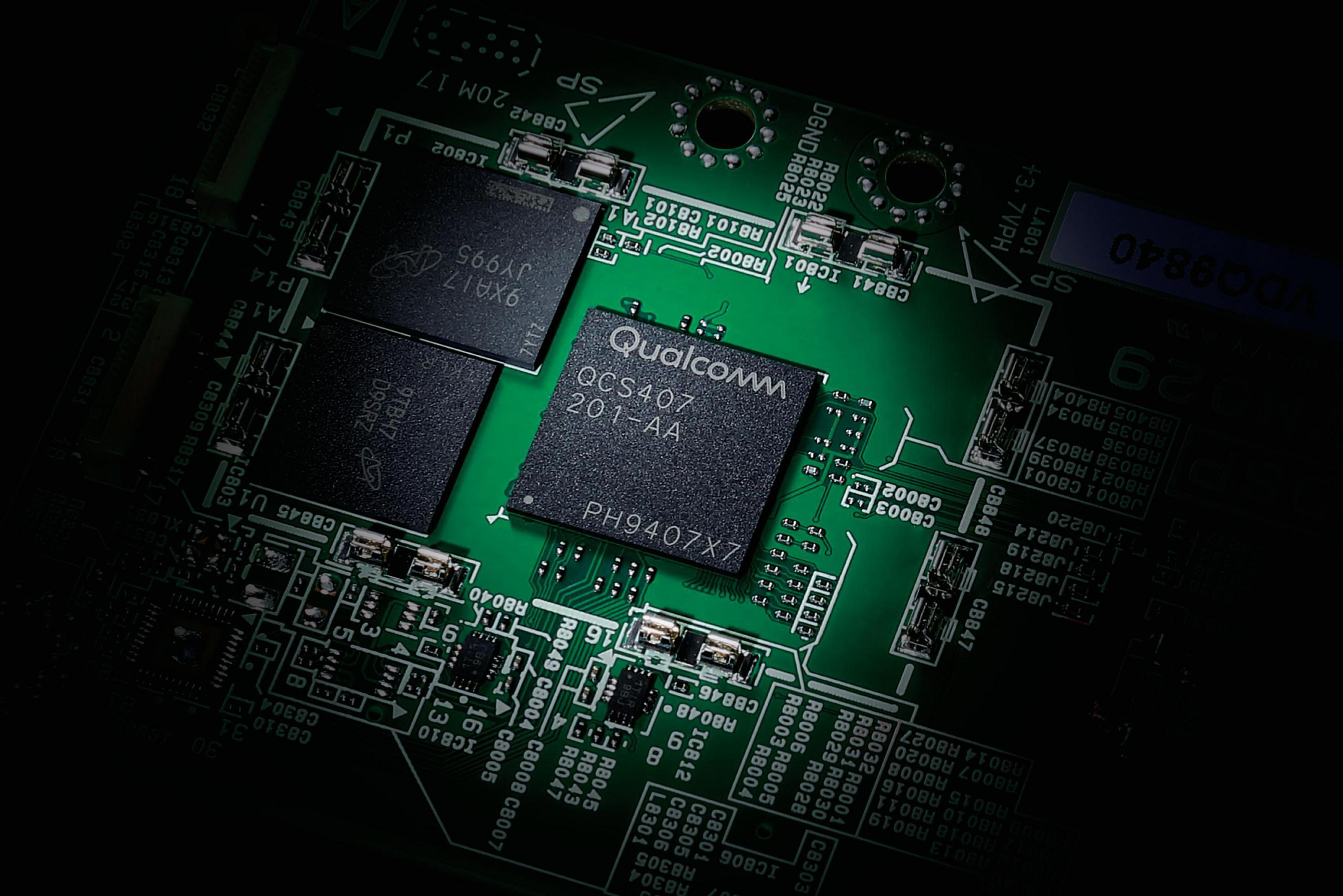 Grüne Leiterplatte mit Qualcomm-Chip und anderen Komponenten, Nahaufnahme, schwarzer Hintergrund.
