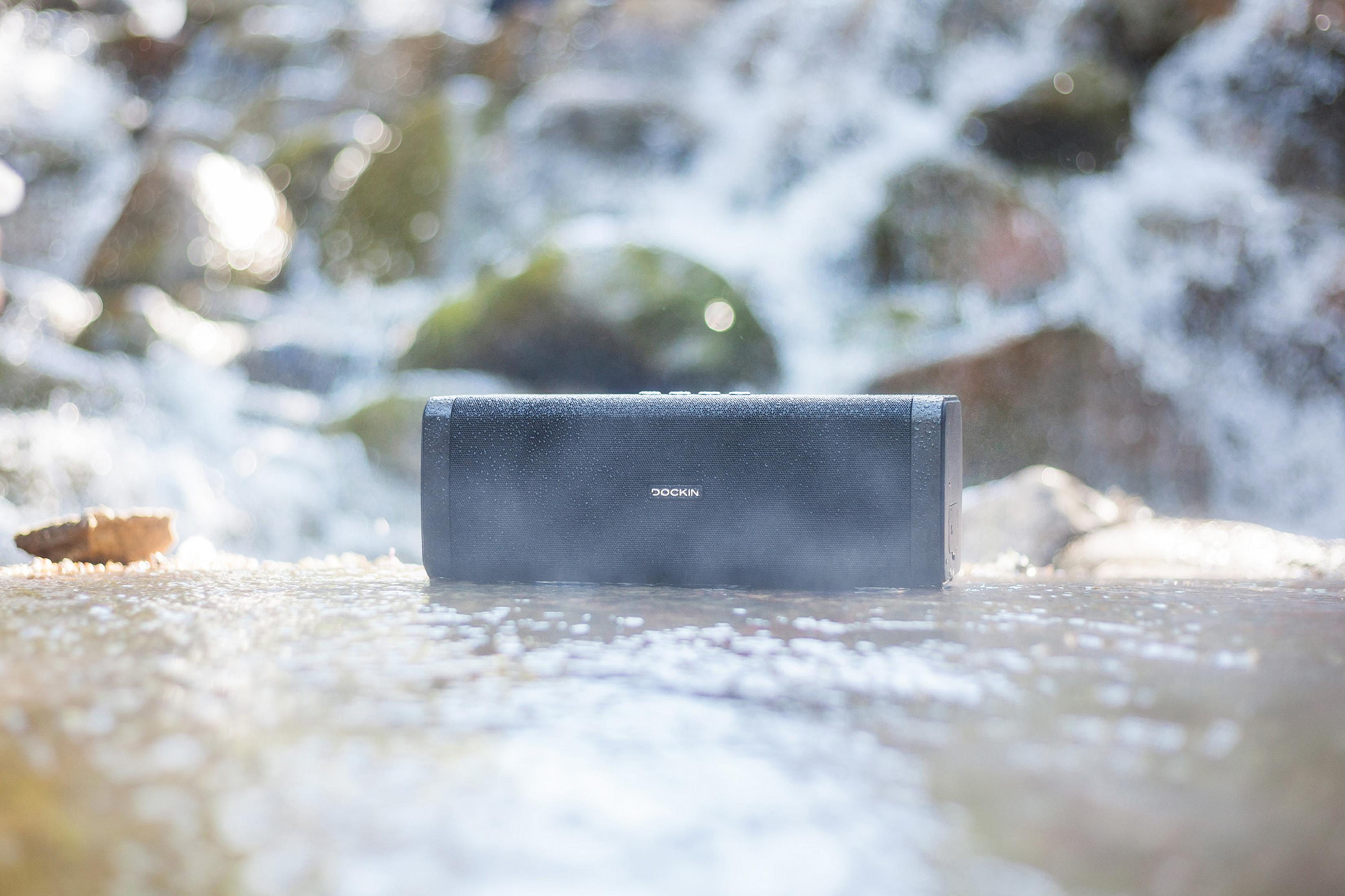 Schwarzer Lautsprecher im Wasser. Wasserfall im Hintergrund.