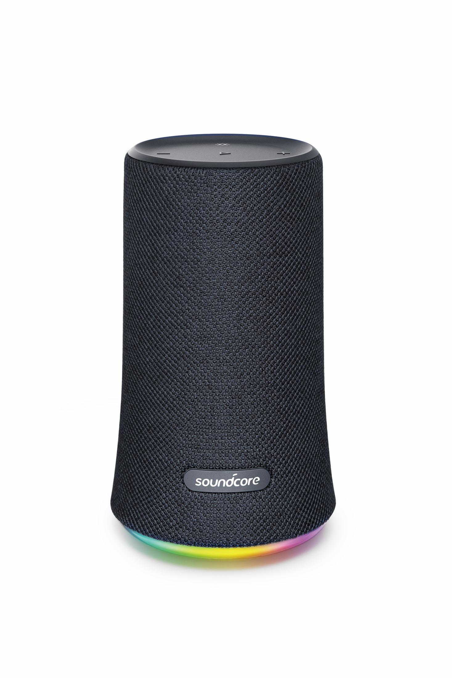 Czarny cylindryczny głośnik z siatkową osłoną. Spód ma kolorowy pierścień świetlny. Białe tło.