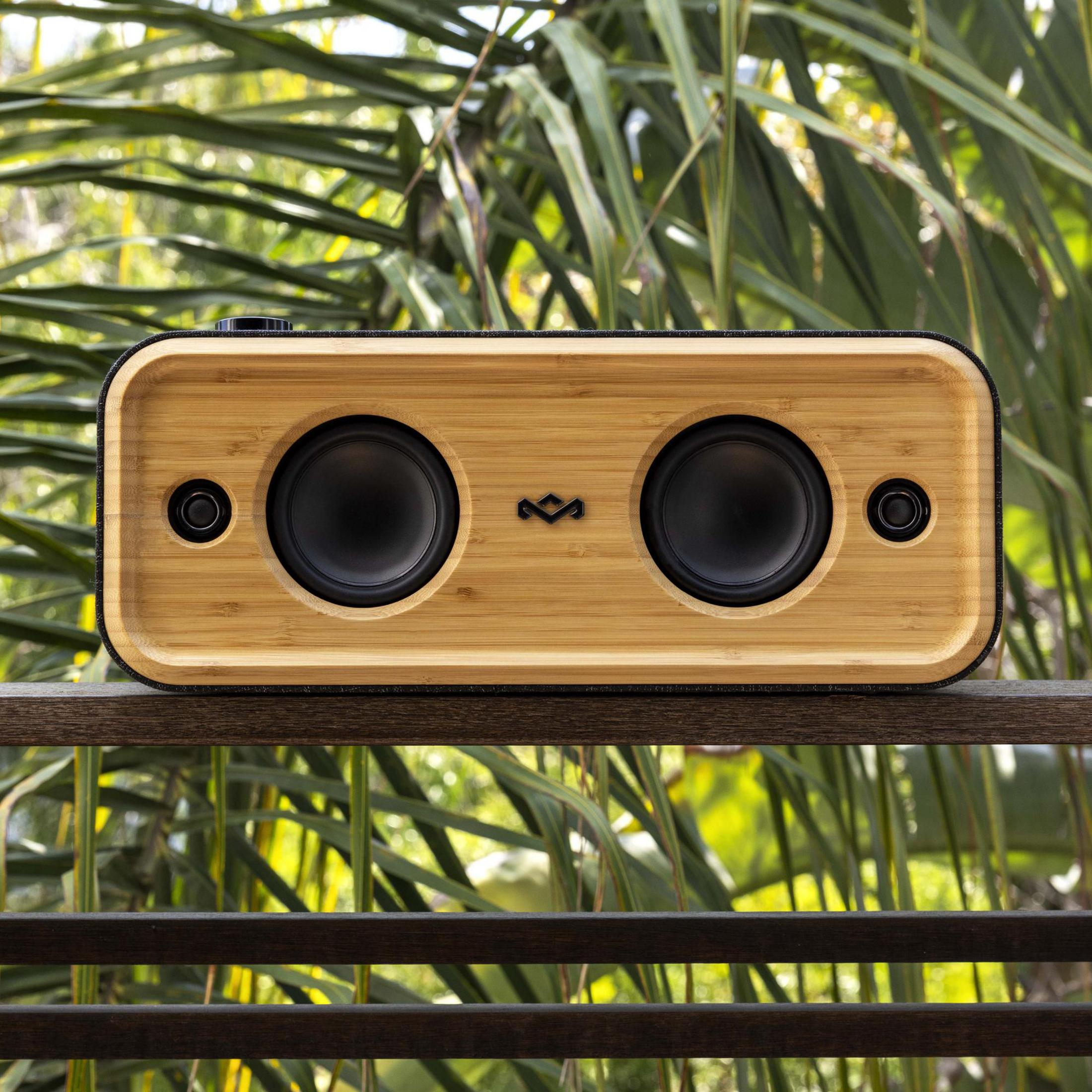 Drewniany głośnik z dwoma czarnymi głośnikami ustawiony na drewnianej balustradzie.
