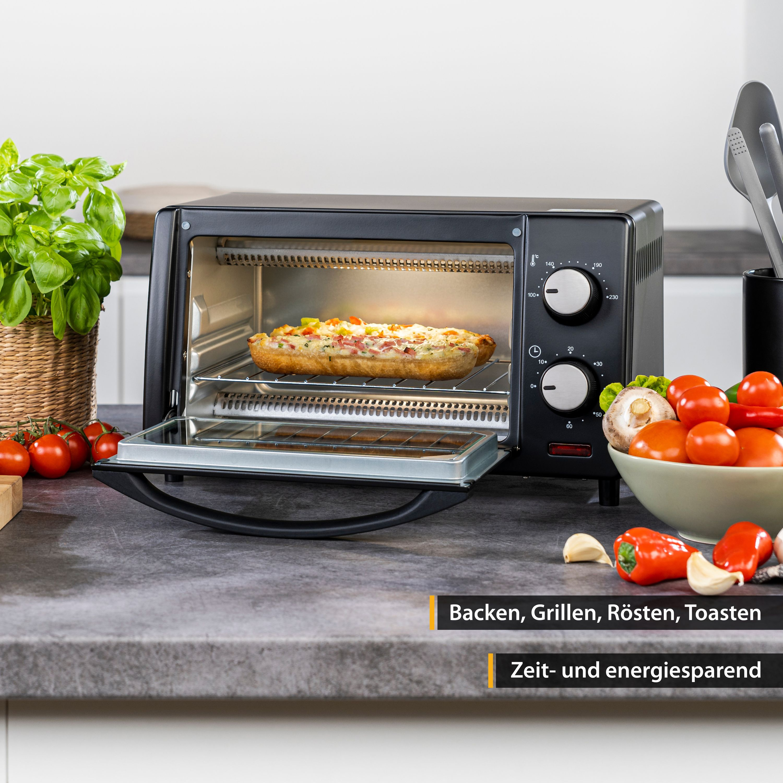 Forno nero con cibo all'interno e verdure intorno. Testo: 'Cuocere, Grigliare, Arrostire, Tostare'.
