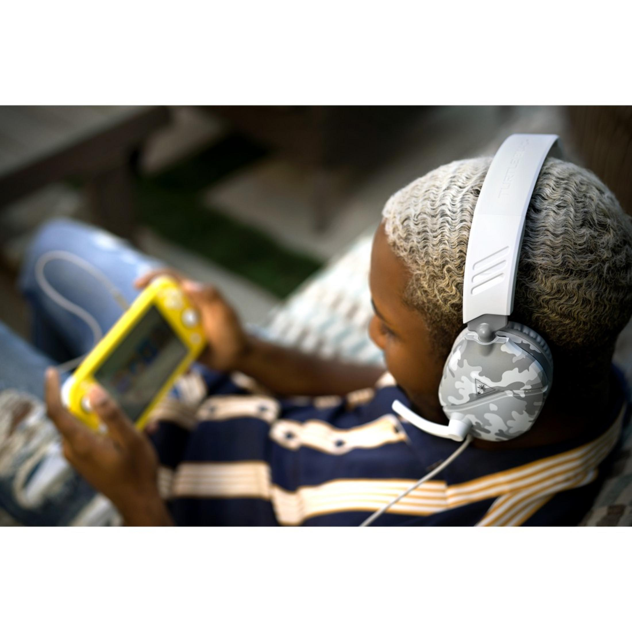 Młoda osoba w słuchawkach grająca na przenośnej konsoli do gier.