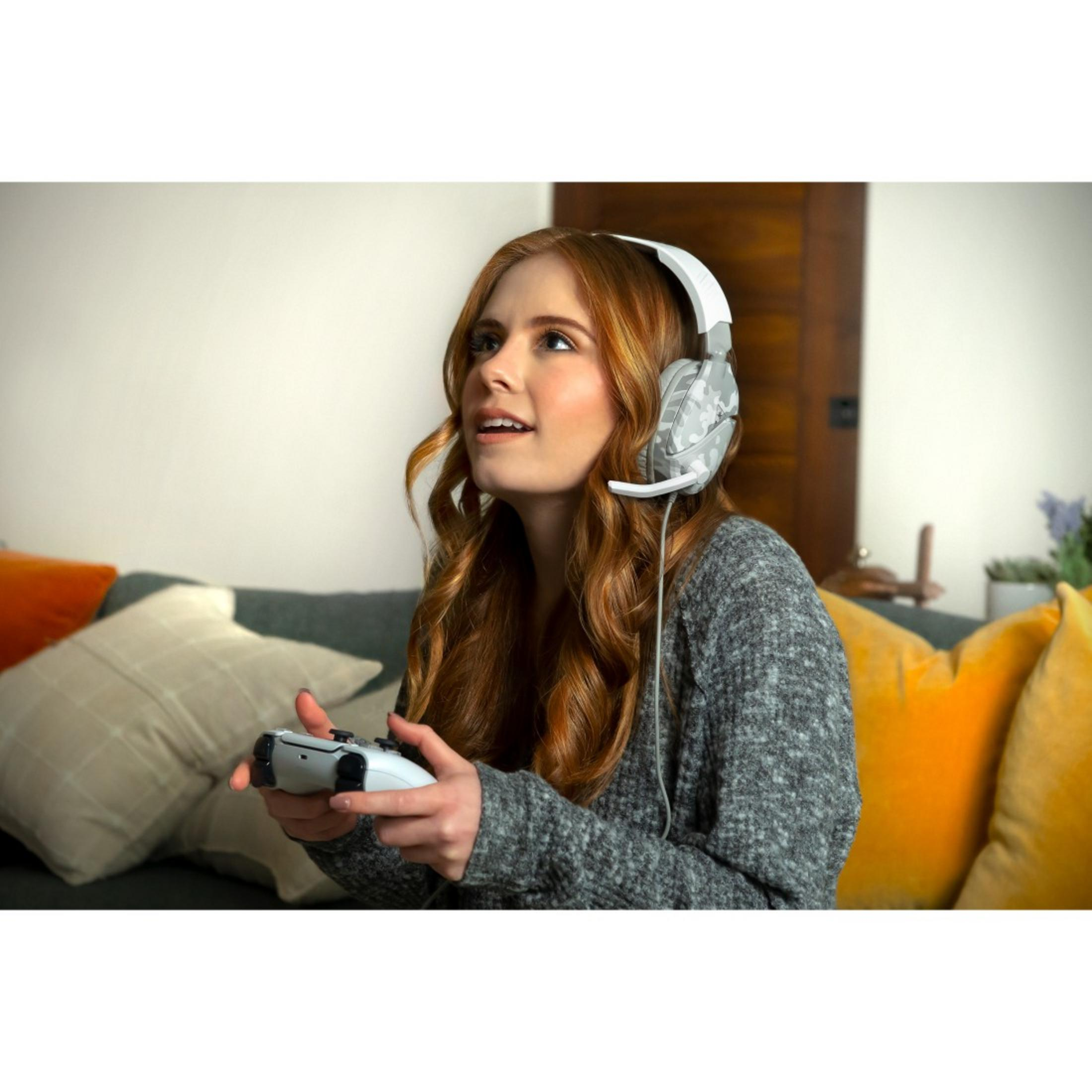 Kobieta z zestawem słuchawkowym gra w grę wideo. Trzyma kontroler, patrzy w górę.