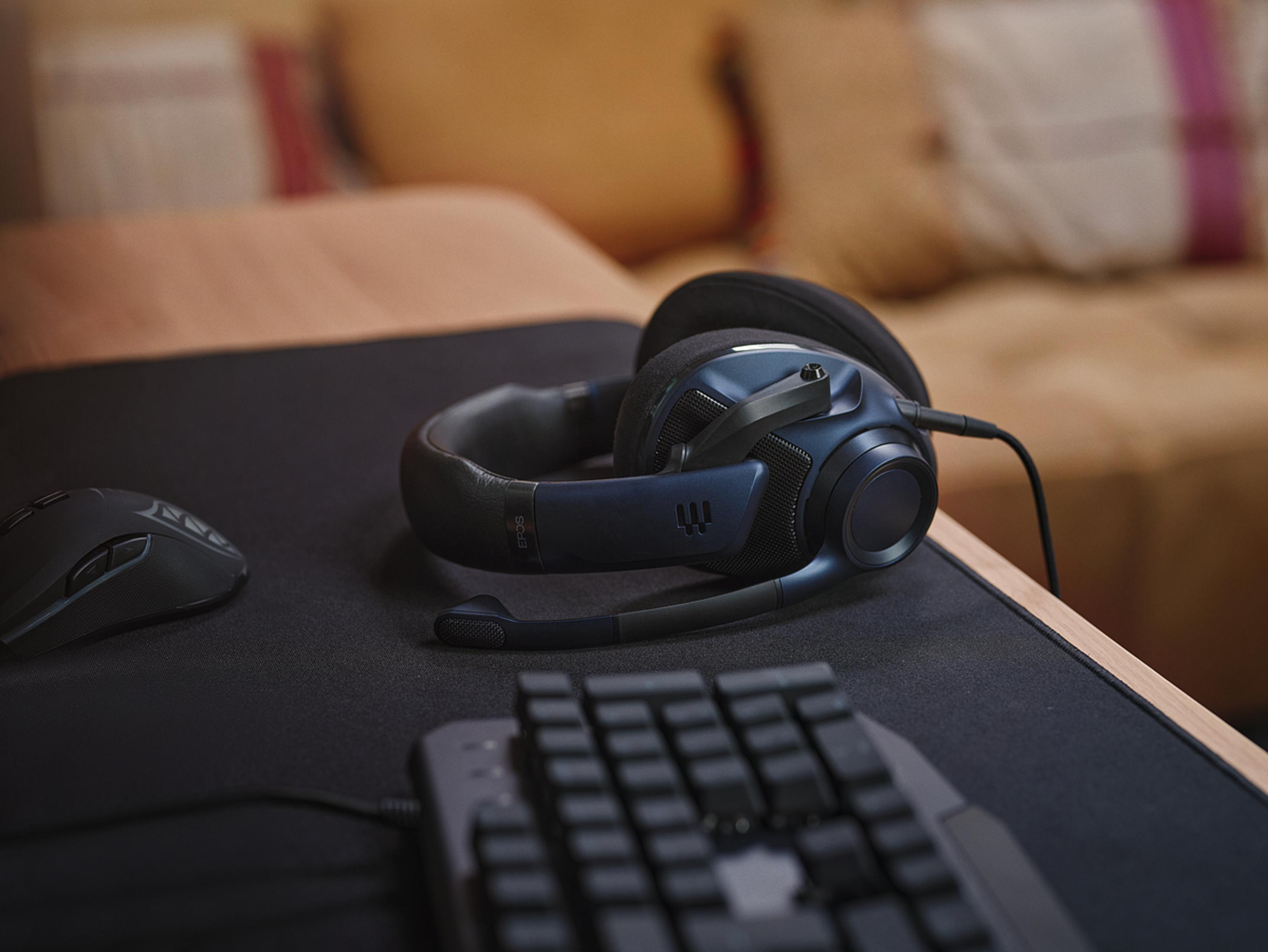 Czarny i niebieski zestaw słuchawkowy dla graczy na biurku z myszką i klawiaturą.