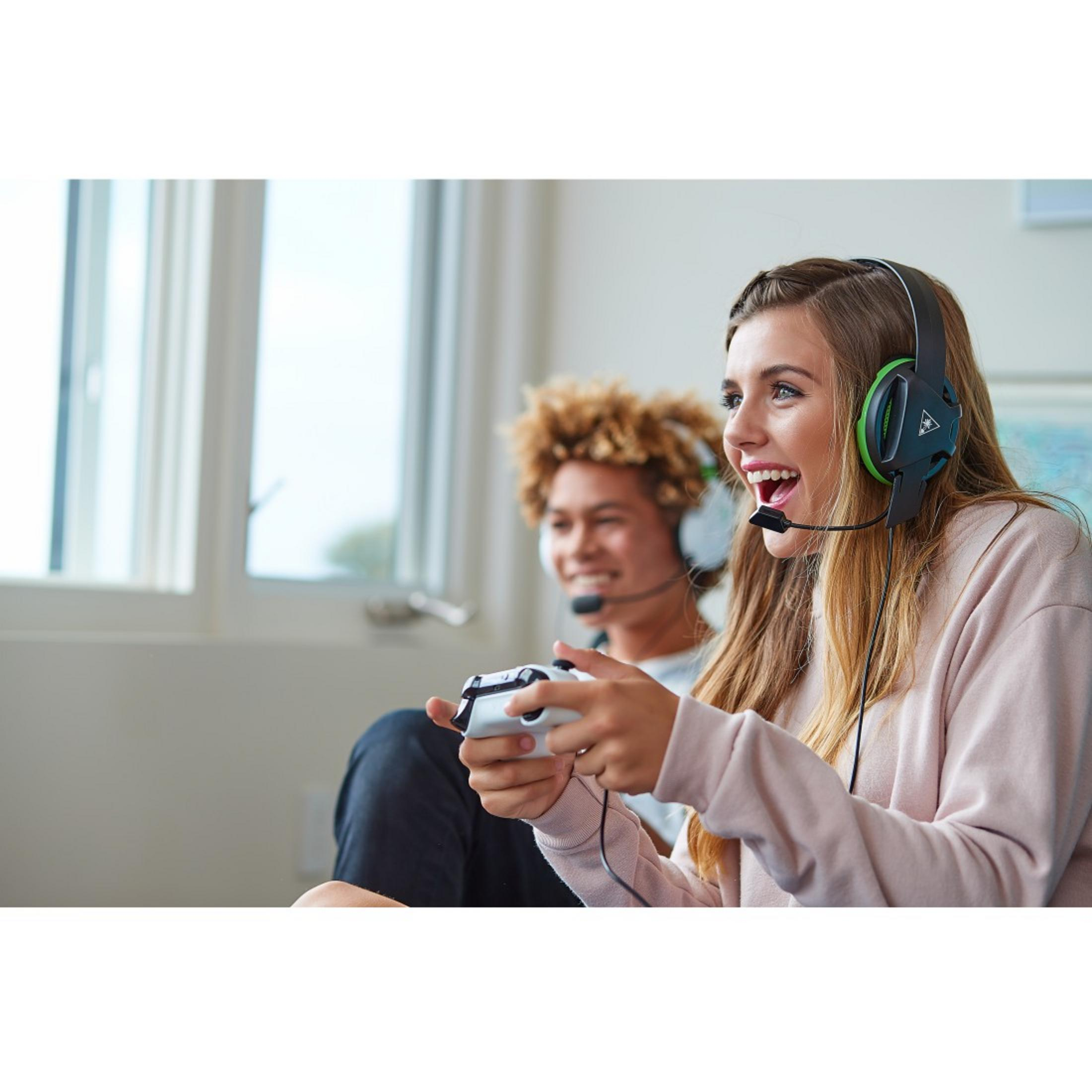 Due giocatori, uno con le cuffie, con un controller. In un salotto.