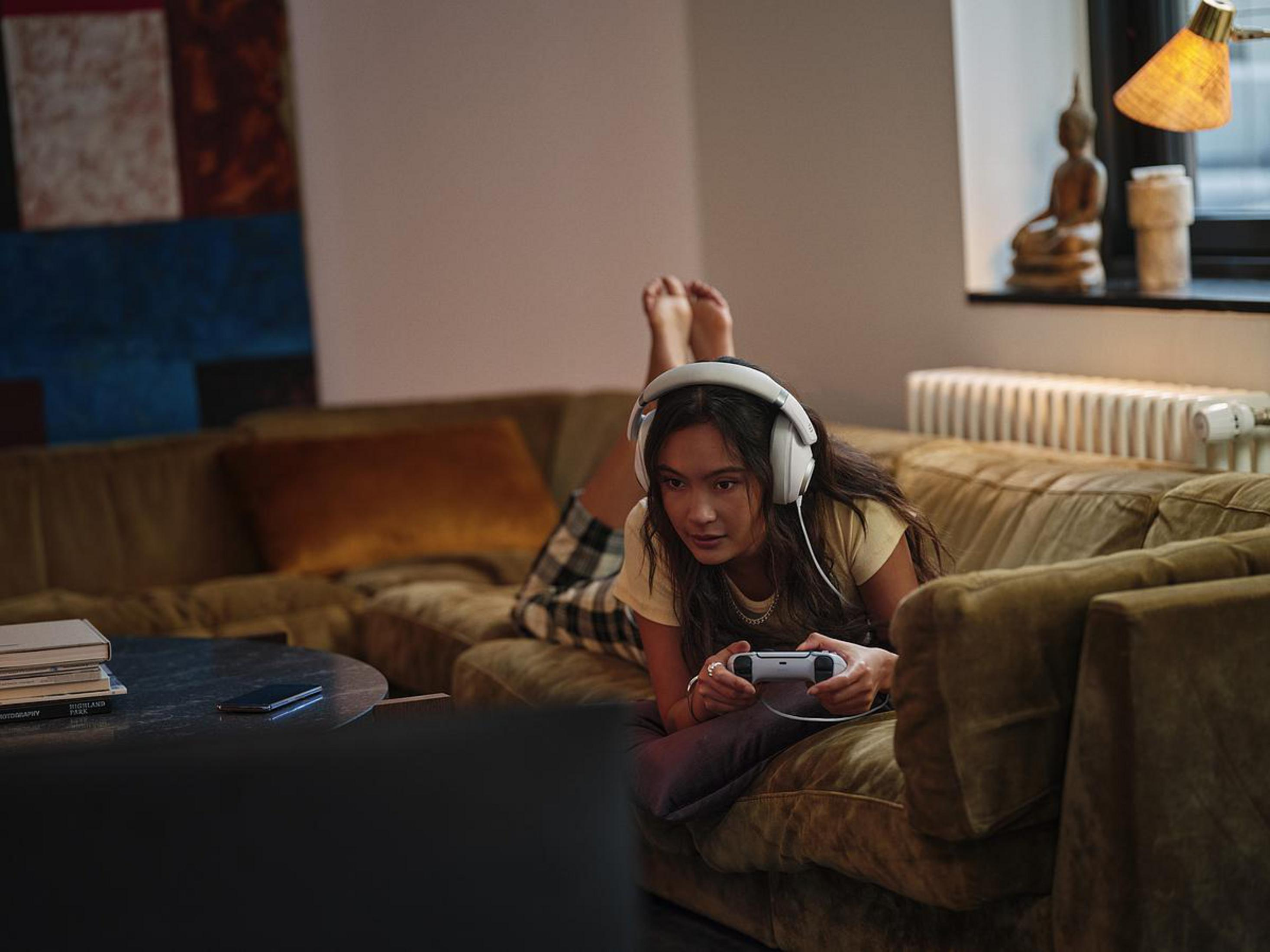 Frau auf Couch, die Videospiel mit weißem Headset spielt.