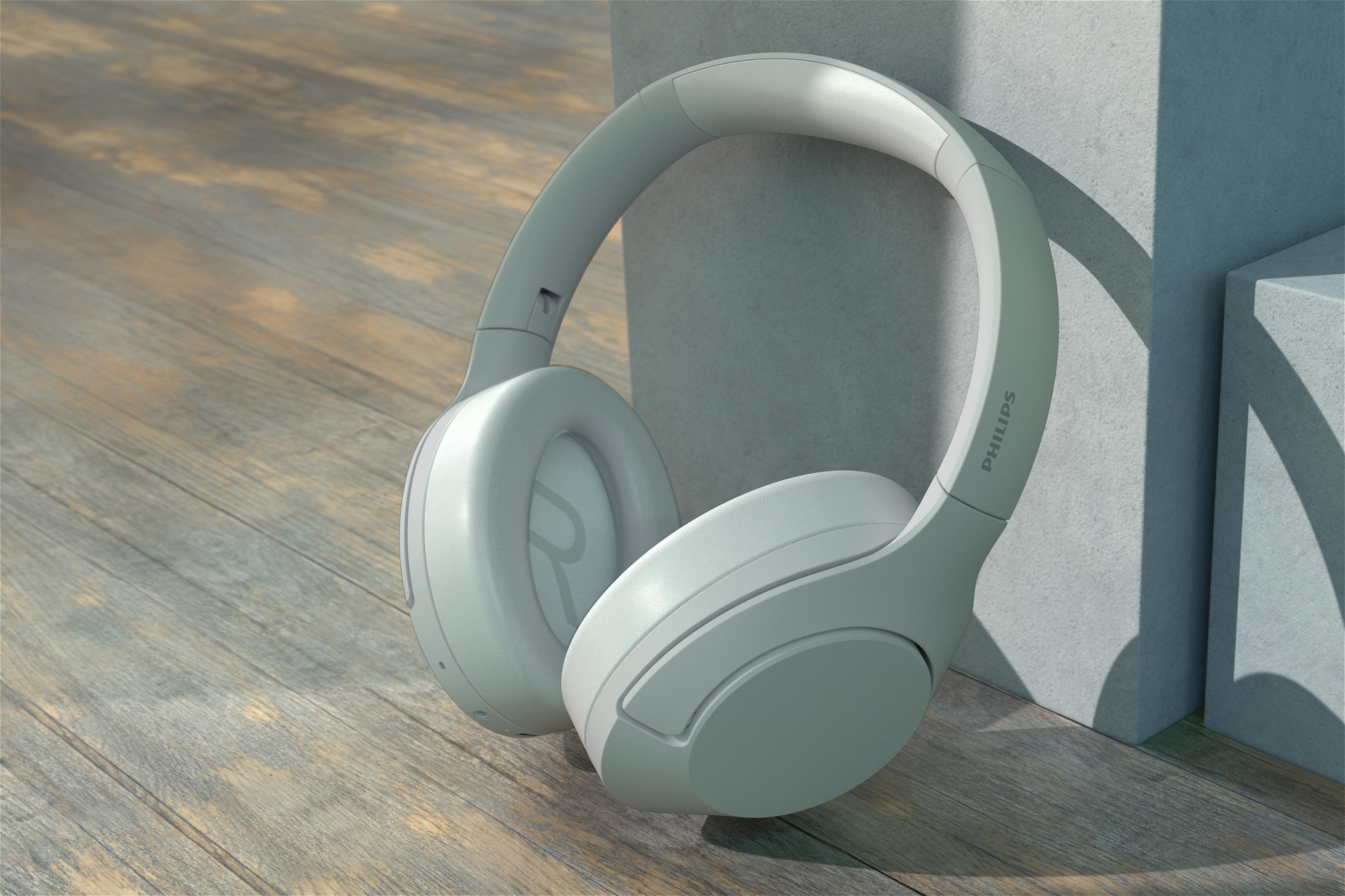 Ein graues Headset liegt auf einer Holzoberfläche in der Nähe einer grauen Wand. Der Markenname ist sichtbar.