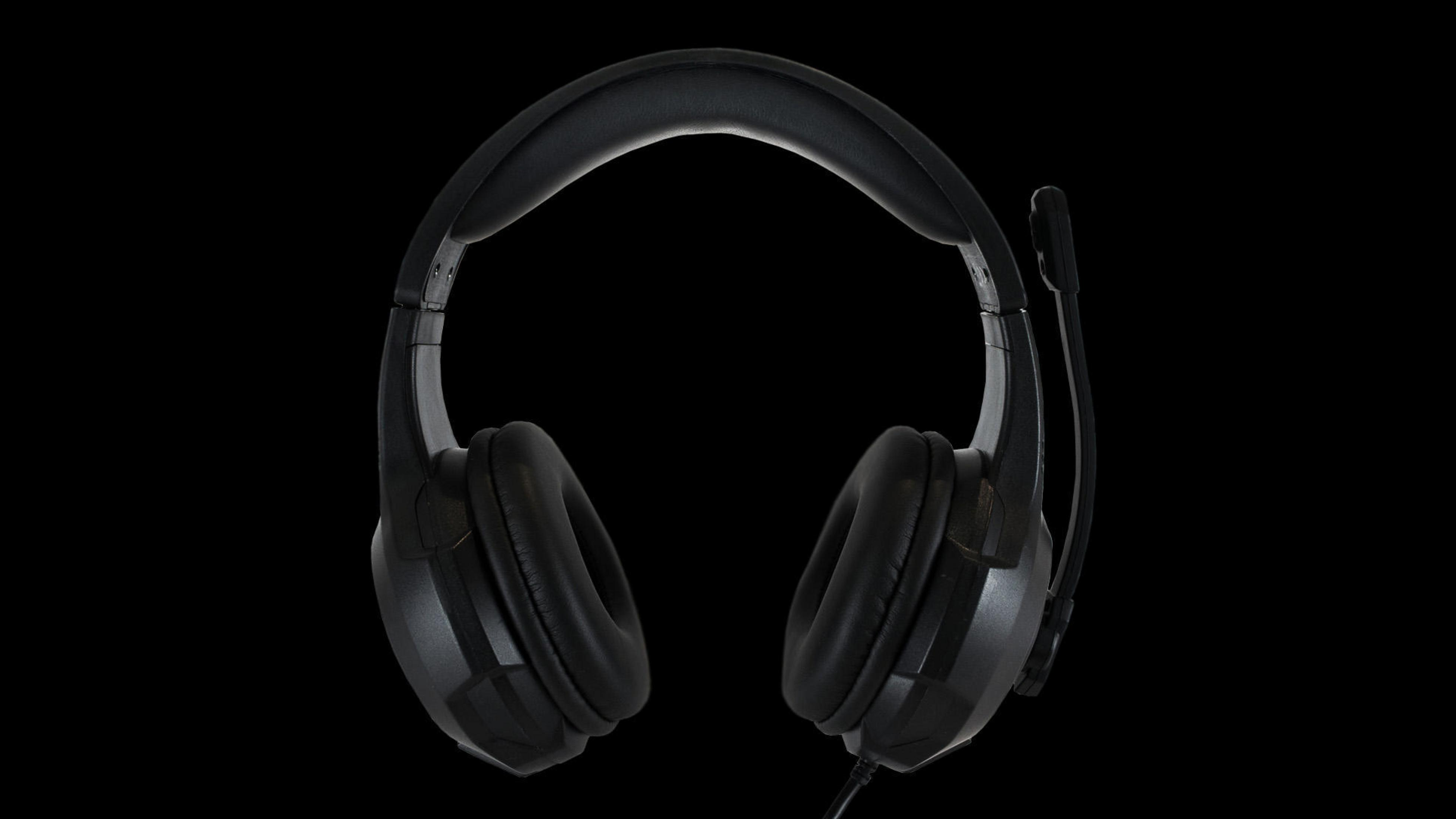 Czarne słuchawki z mikrofonem na czarnym tle. Całkowity projekt jest prosty.