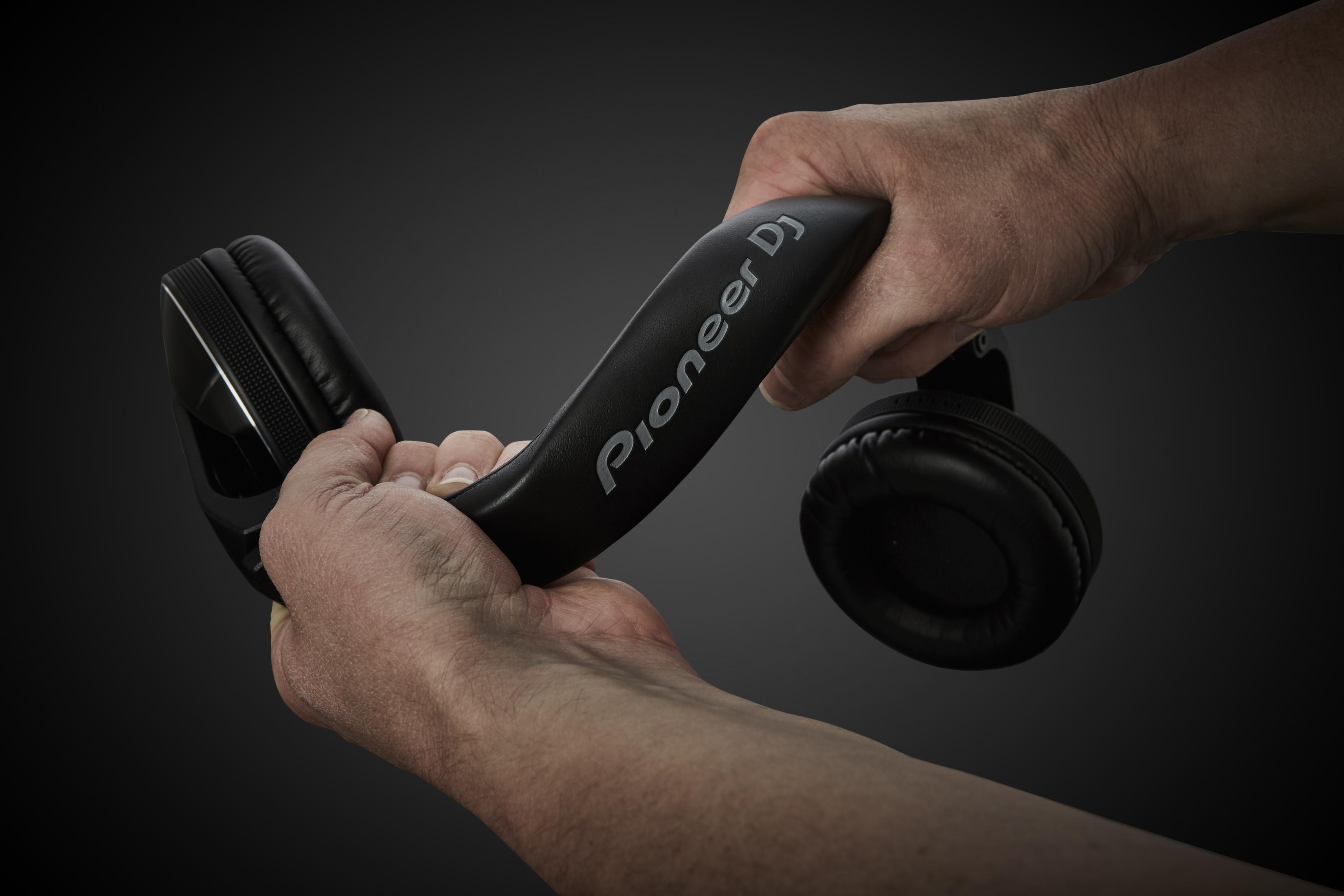 Dłonie zginające czarne słuchawki Pioneer DJ, pokazujące elastyczność pałąka.