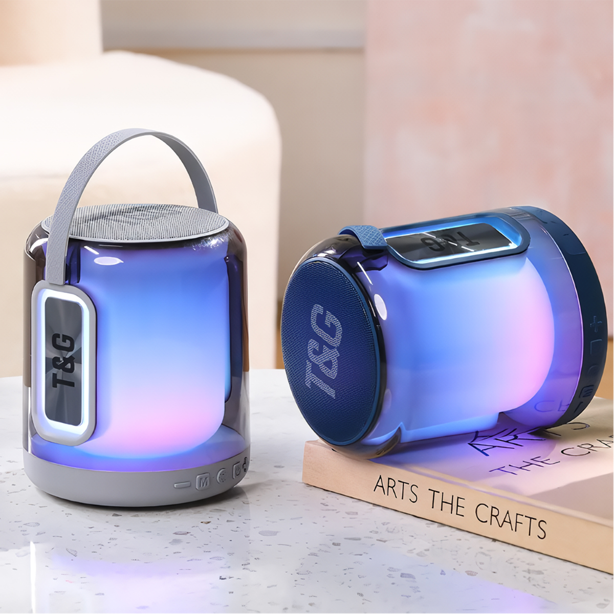 Dos altavoces Bluetooth T&G iluminados sobre una mesa, uno horizontal y otro vertical, con texto.