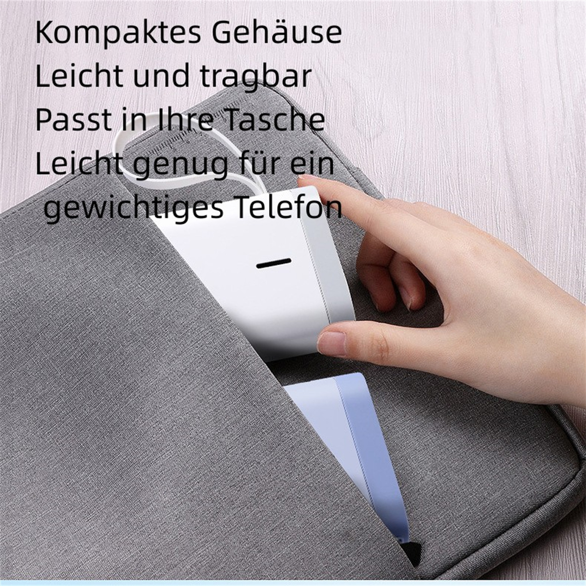 Hand steckt weißen Etikettendrucker in eine graue Tasche. Text auf der Tasche.