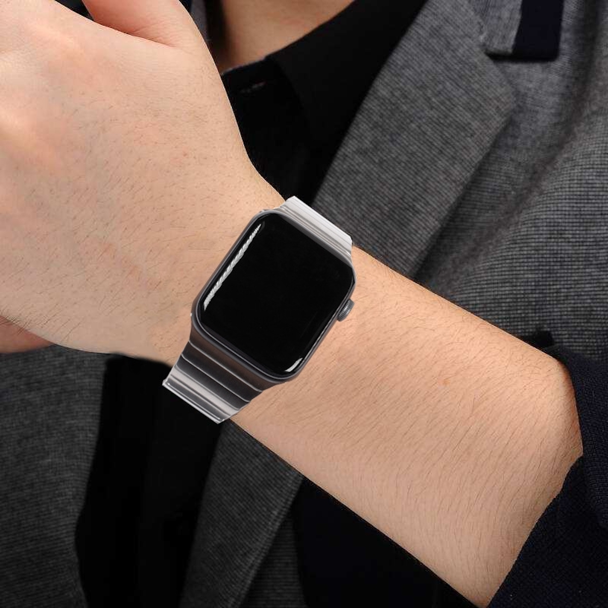 Das Handgelenk einer Person mit einem gestreiften Apple Watch-Armband in Silber und Schwarz.