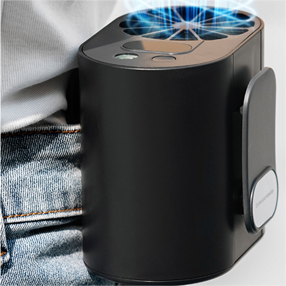 Schwarzer tragbarer Ventilator an einer Jeansjacke befestigt. Blaues Licht geht vom Ventilator aus.
