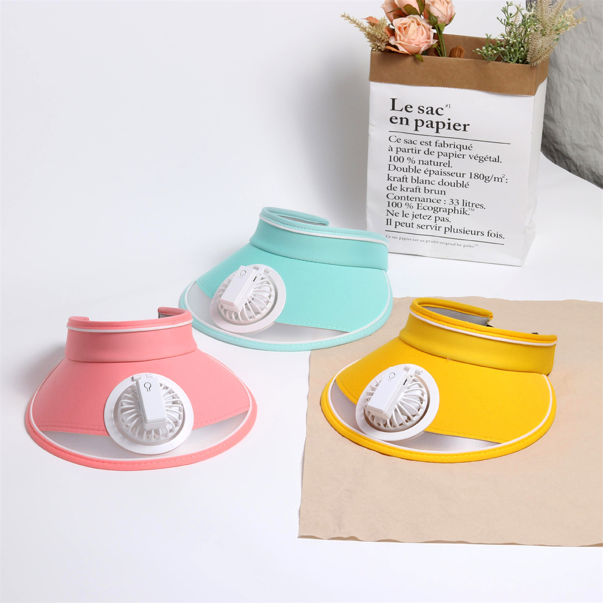 Drei bunte Sonnenblenden mit Ventilatoren, rosa, blau und gelb.
