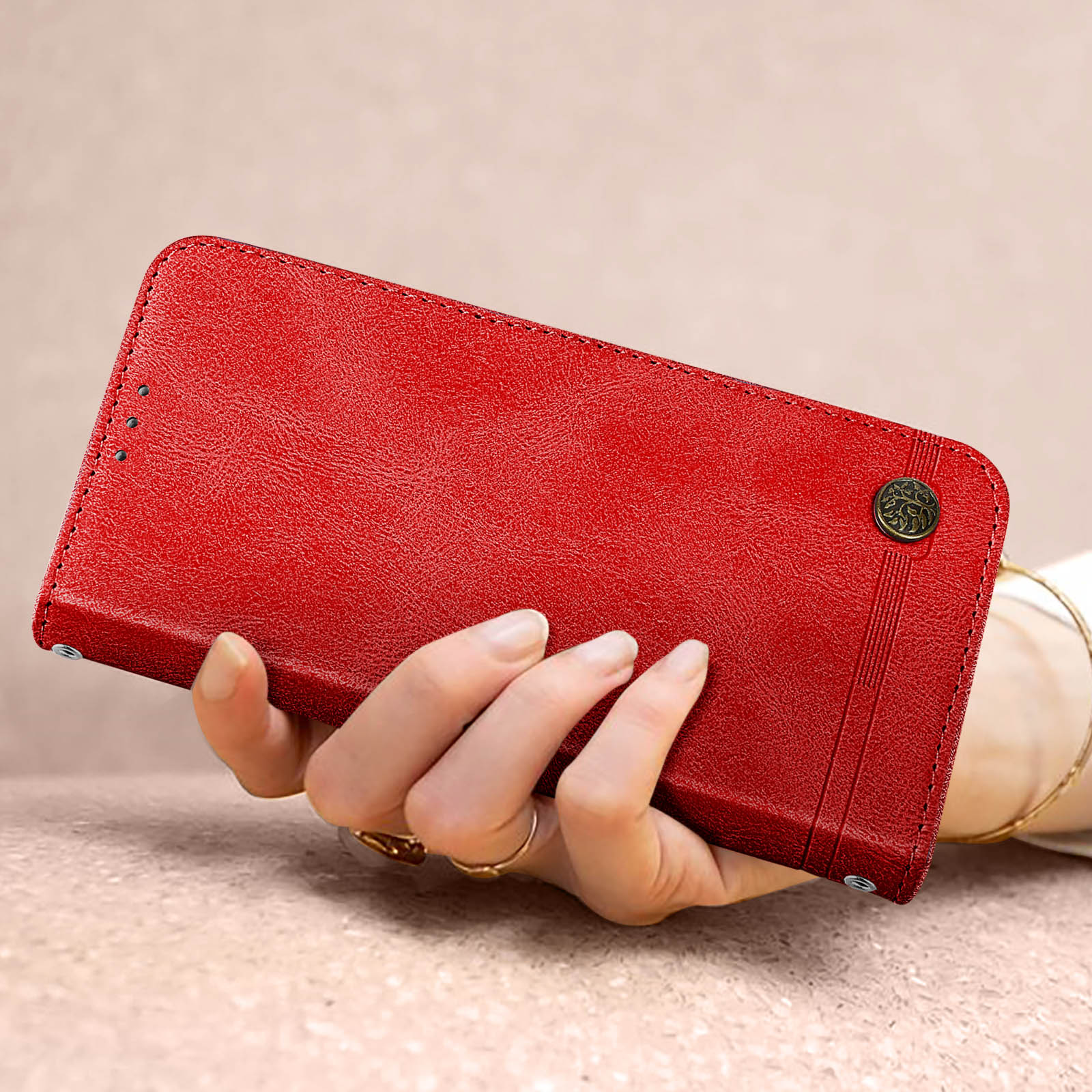 Eine rote Leder-Handyhülle, die von einer Hand gehalten wird. Die Hülle hat einen Schnappverschluss und ein genähtes Design.