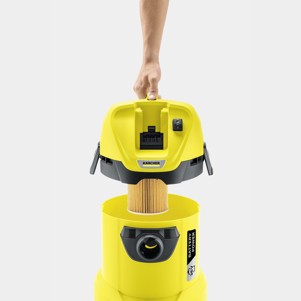 Un aspirateur Kärcher jaune avec un filtre en cours d'insertion. Une main tient le dessus.