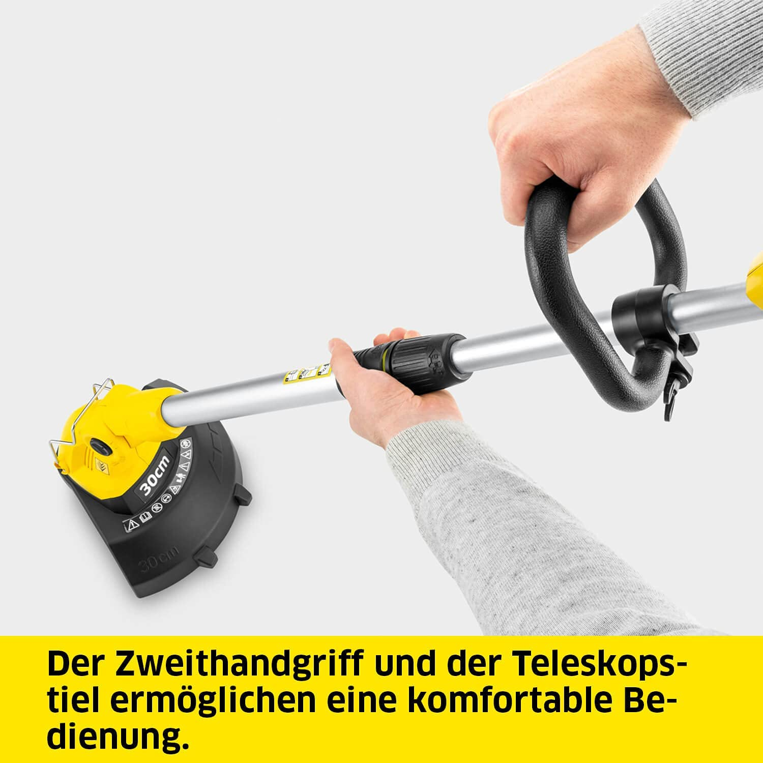 Dłonie trzymają żółto-czarny trymer. Tekst: Der Zweithandgriff und der Teleskopstiel...