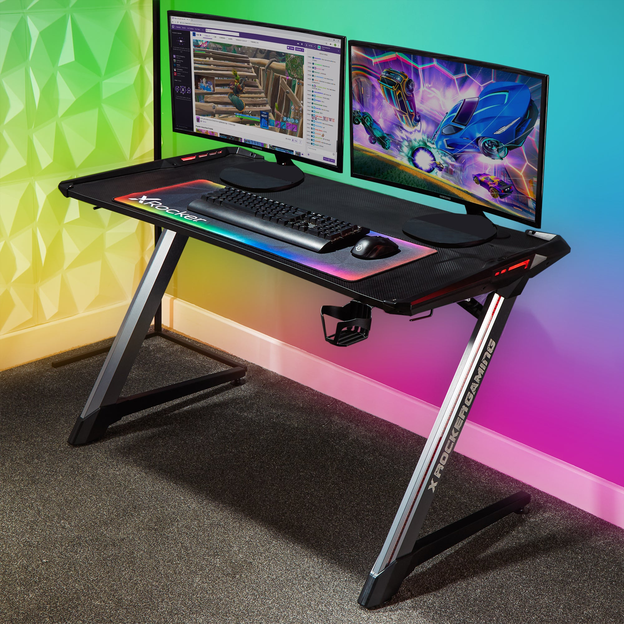 Ein Gaming-Schreibtisch mit zwei Monitoren und Gaming-Zubehör, beleuchtet mit bunten Lichtern.