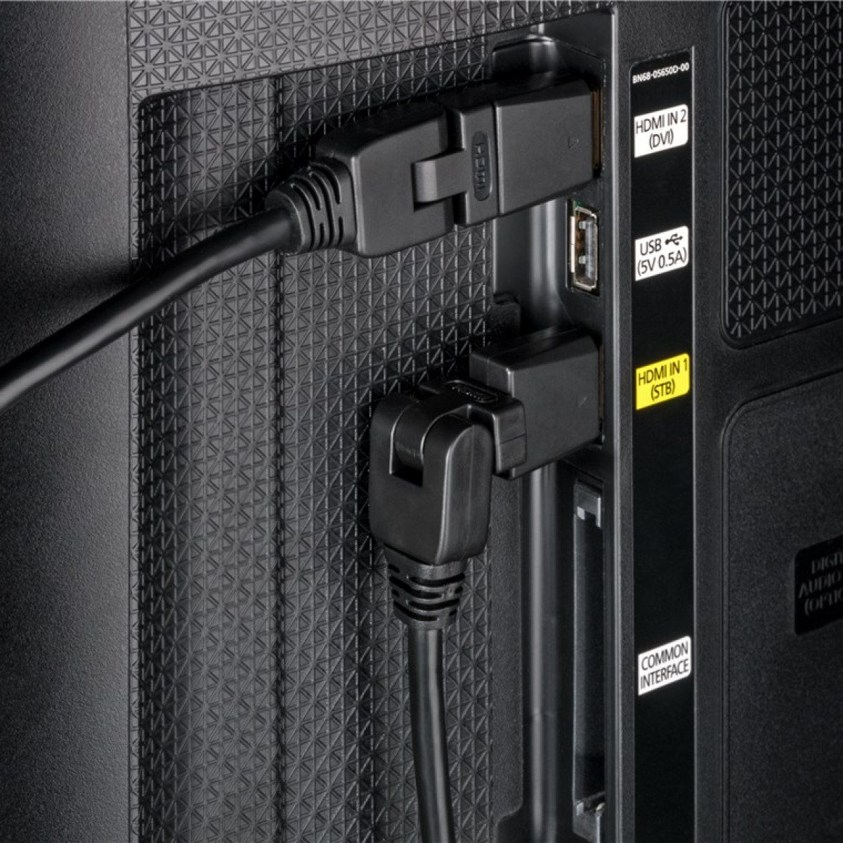 Nahaufnahme von TV-Anschlüssen mit eingesteckten HDMI-Kabeln, auf schwarzer Oberfläche.