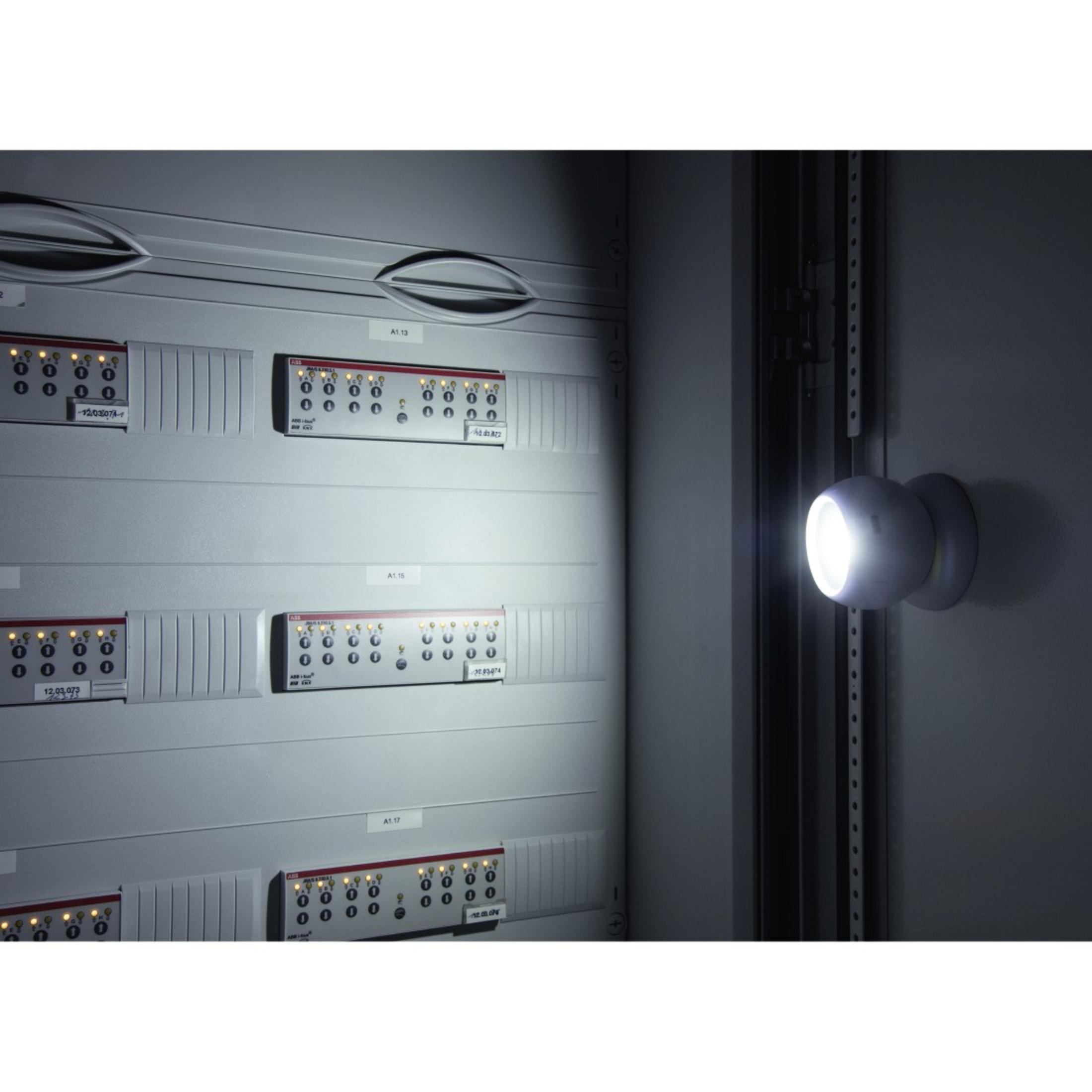 Weißes Licht an grauer Metallplatte, in dunklem Raum.