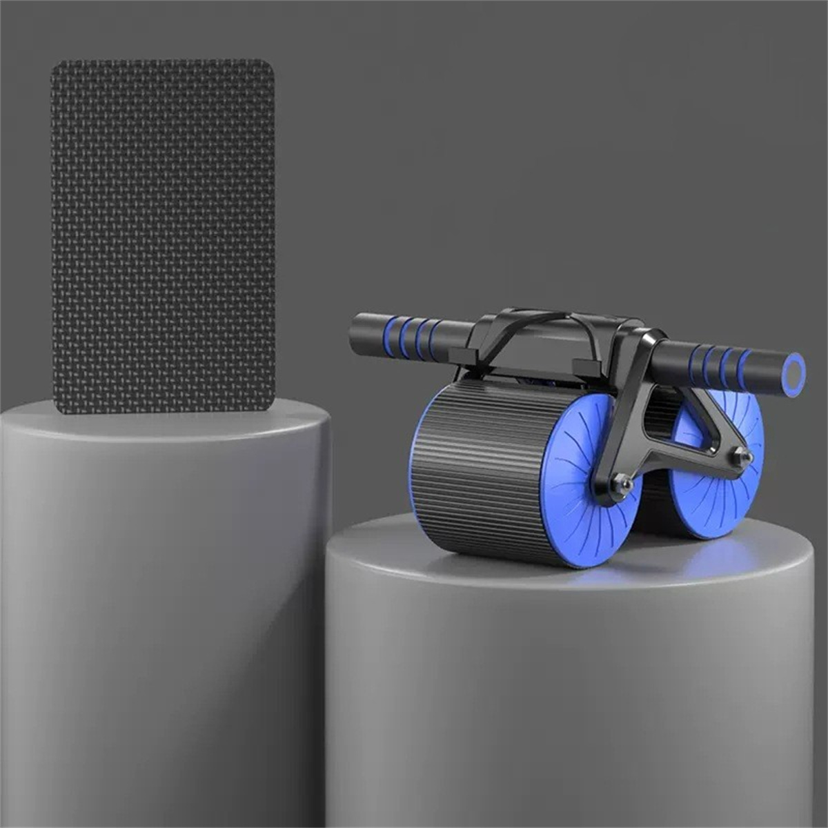 Ab-Roller und Trainingsmatte auf grauem Podest, mit grauem Hintergrund.