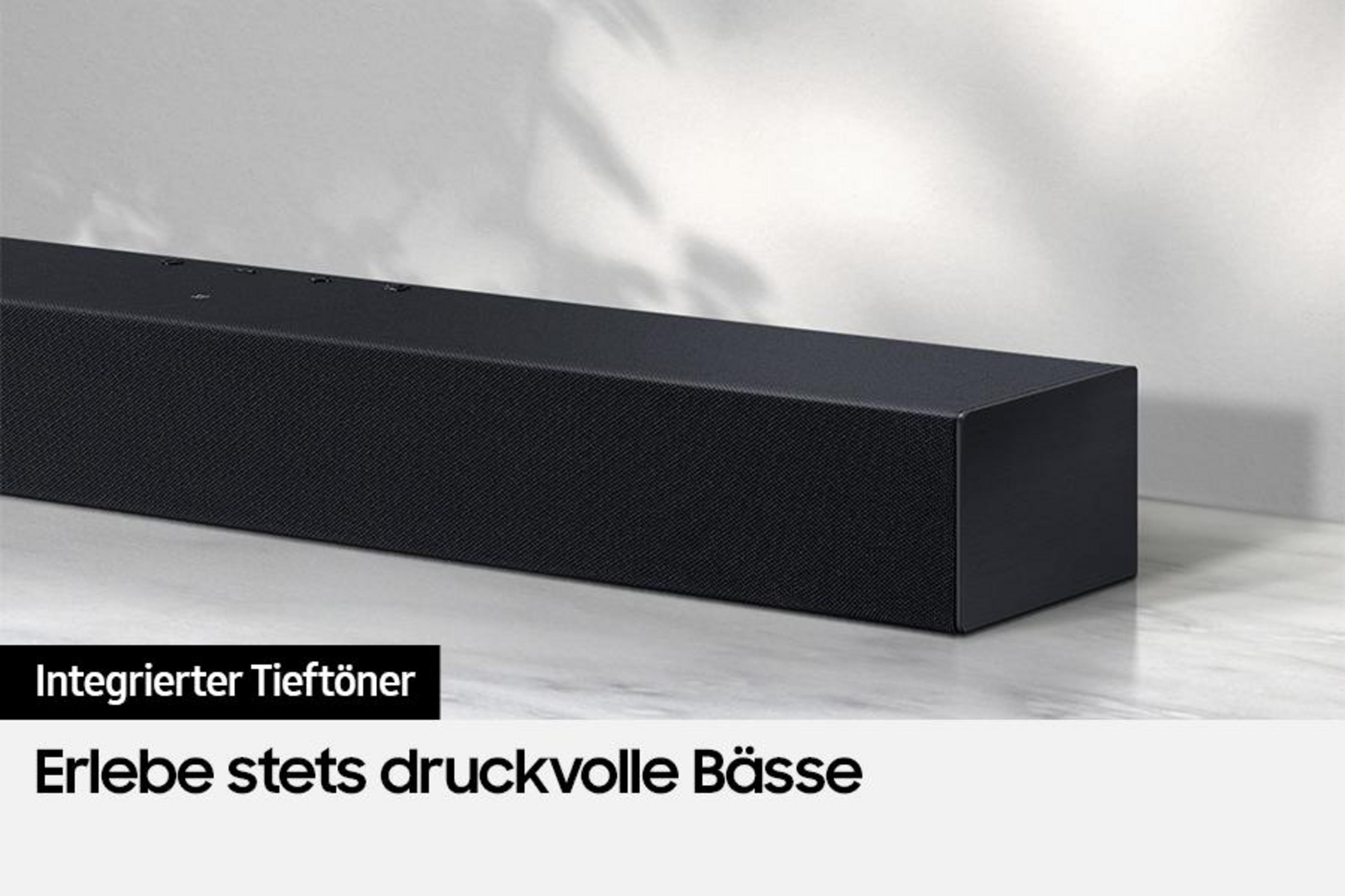 Czarny soundbar ze zintegrowanym subwooferem. Stoi na białej powierzchni. Widoczne jest logo marki.