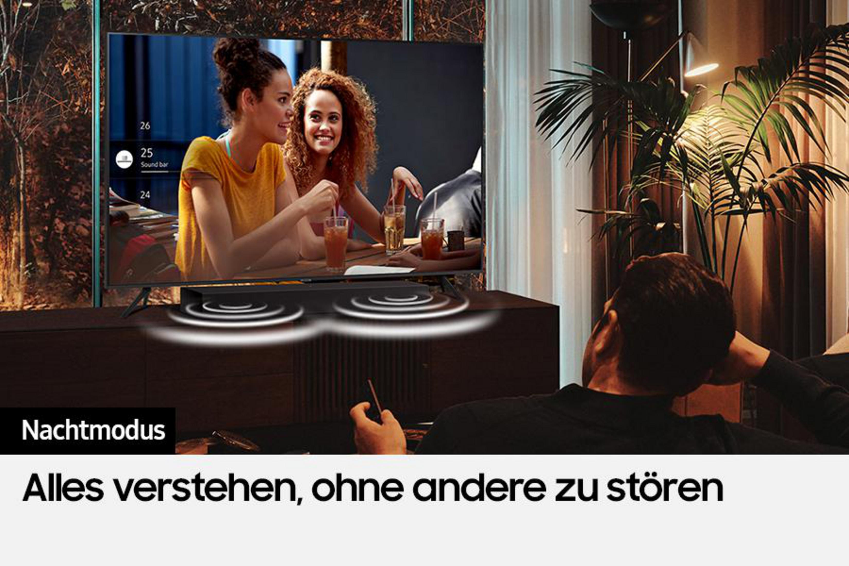 Dwie kobiety oglądają TV. Mężczyzna leży, patrząc na ekran. Soundbar pod TV.