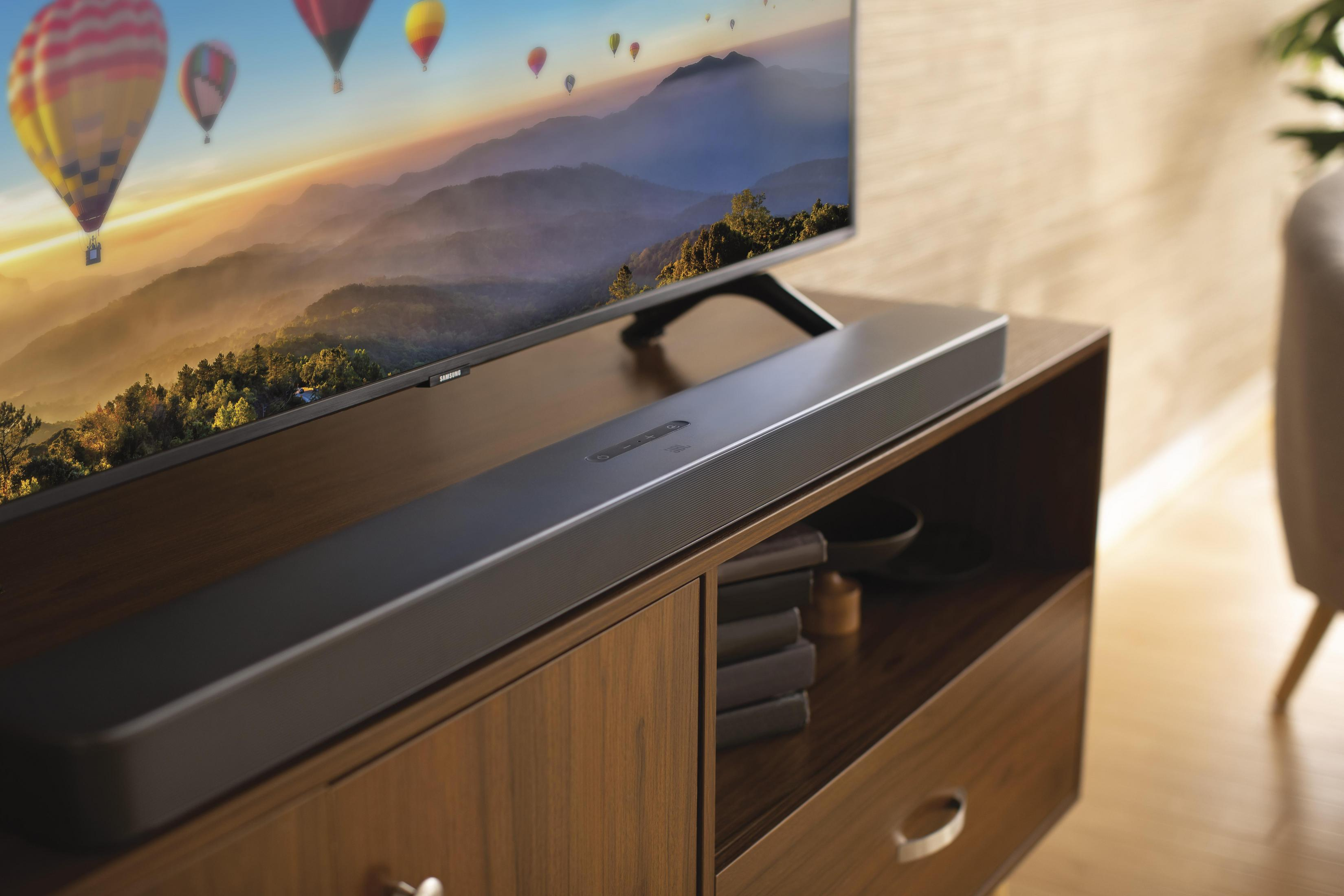 Ahşap bir dolapta ses çubuğu, manzaralı bir görüntü gösteren TV, iç mekan ayarı.