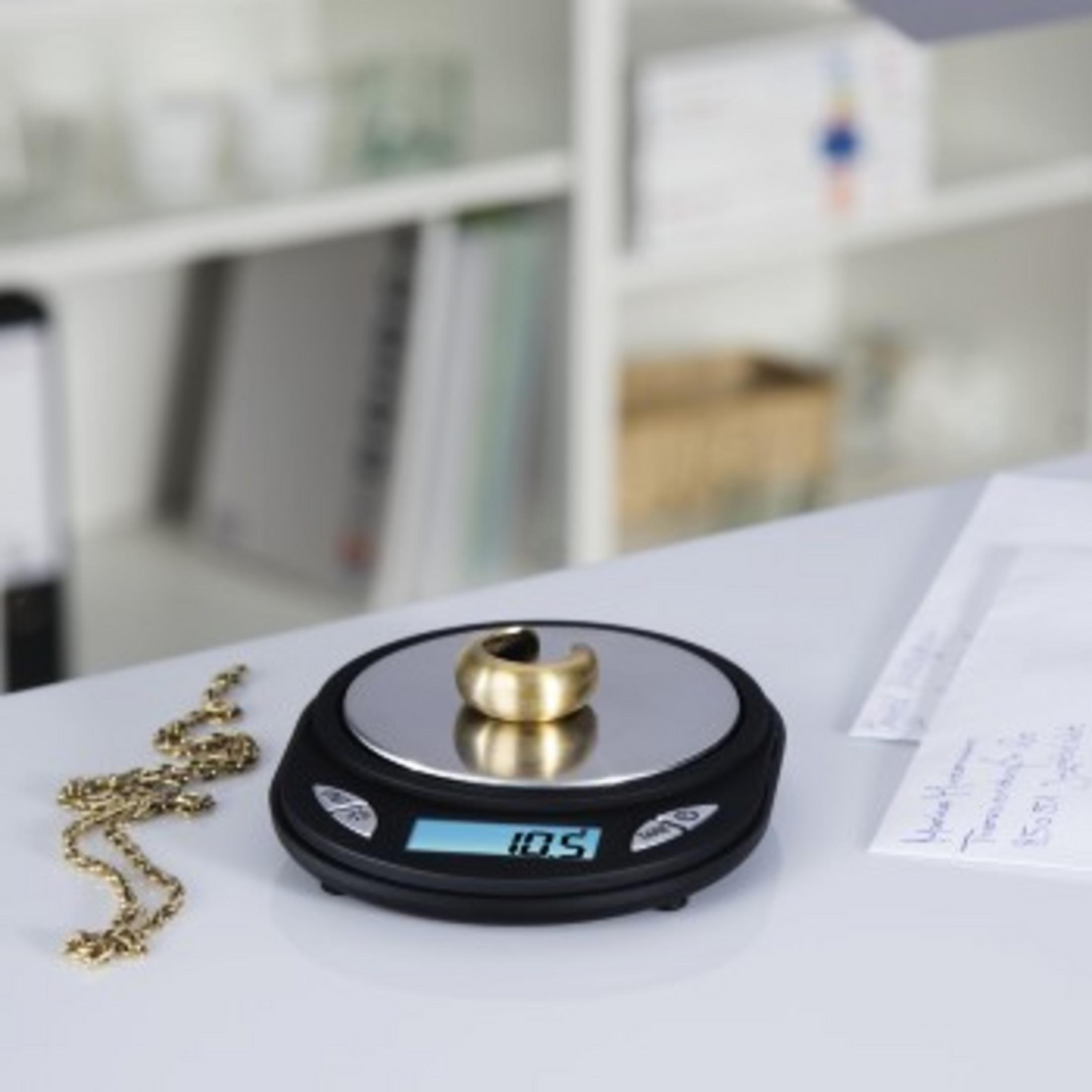 Una bilancia con anello d'oro, catena d'oro e documenti.
