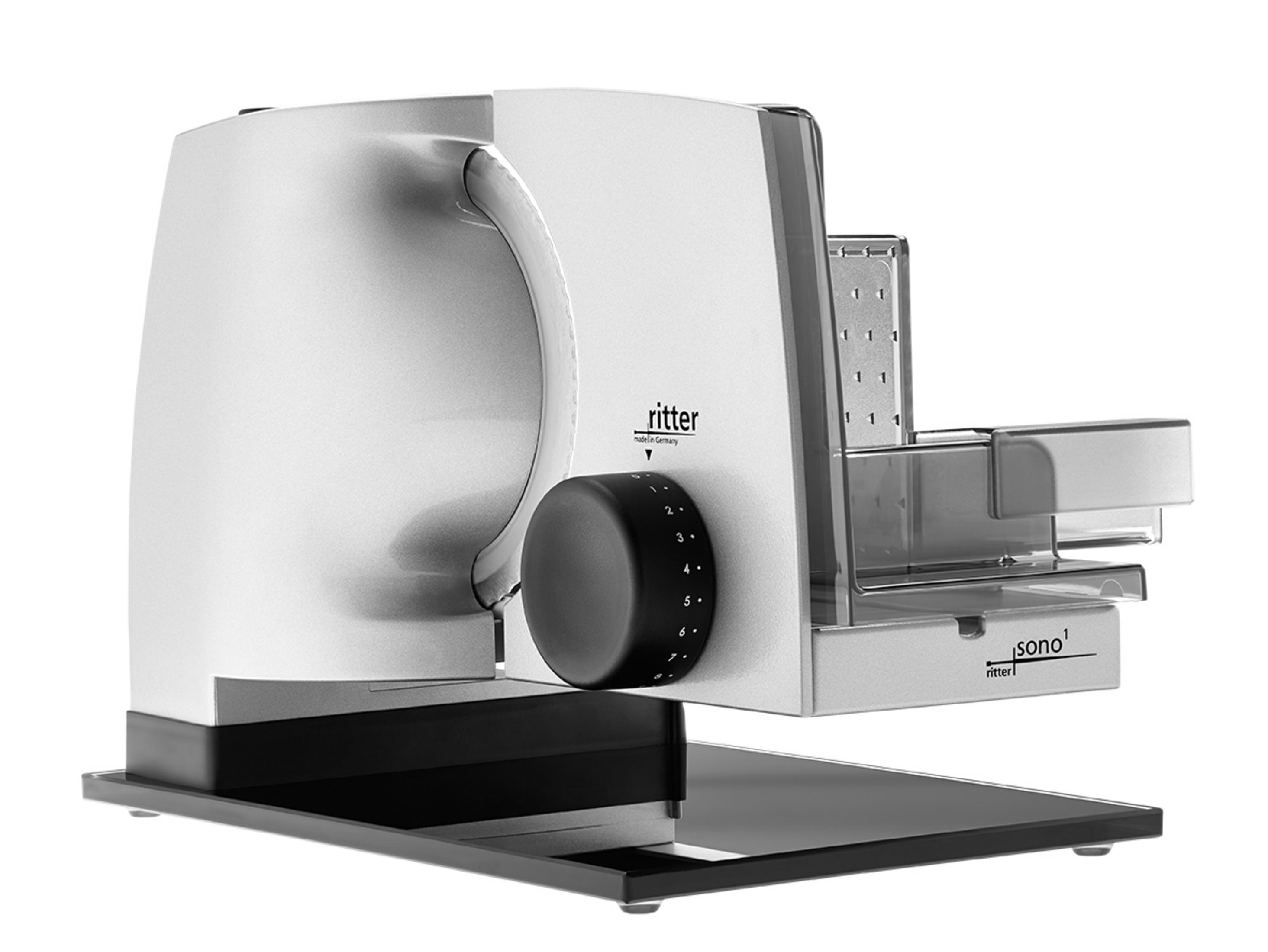 Srebrna krajalnica do mięsa. Ma czarny pokrętło, przezroczysty uchwyt na żywność i czarną podstawę.