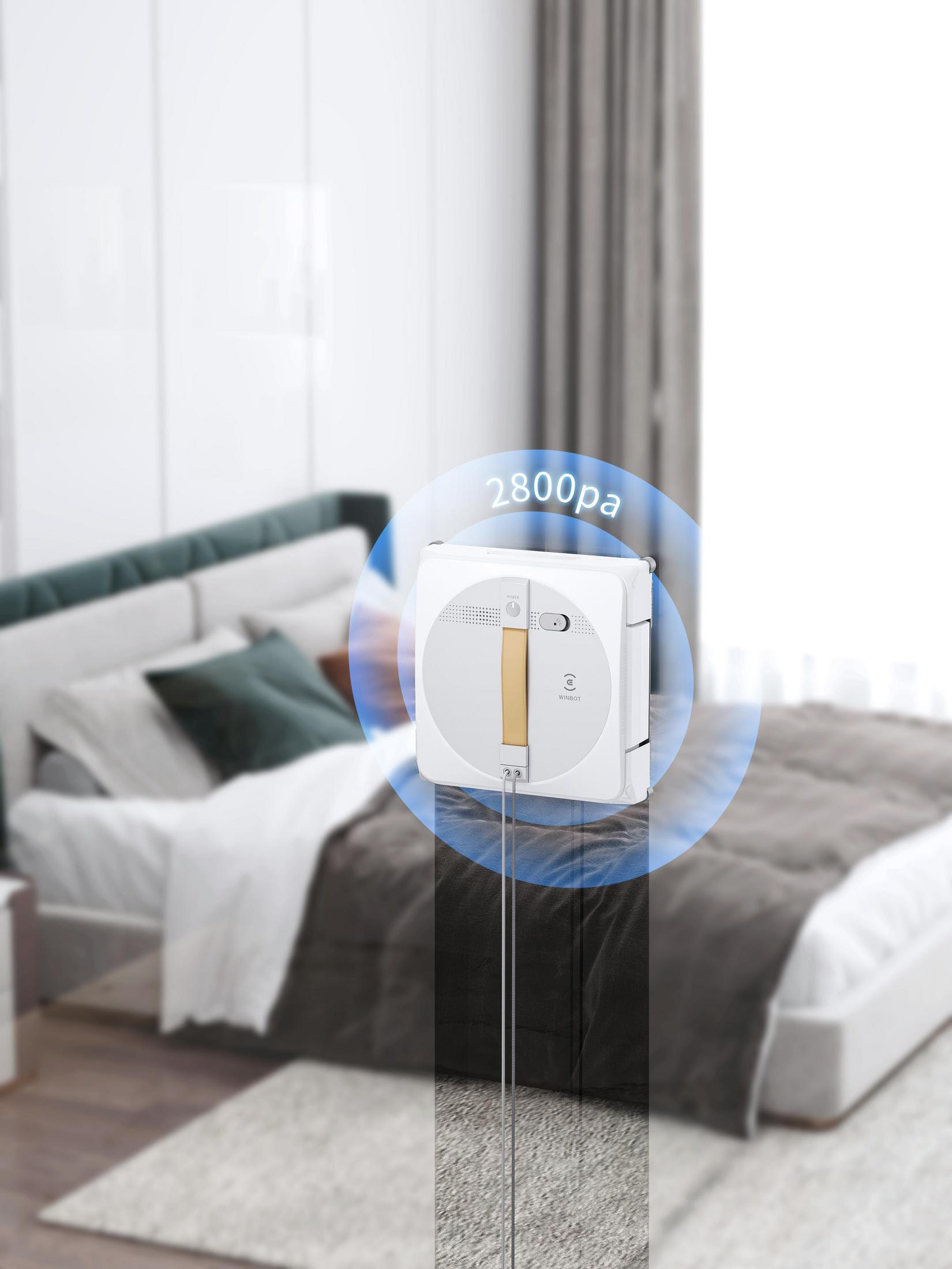 Weißer Fensterputzroboter in einem Schlafzimmer. Ein blauer Kreis zeigt 2800 Pa Saugkraft an.