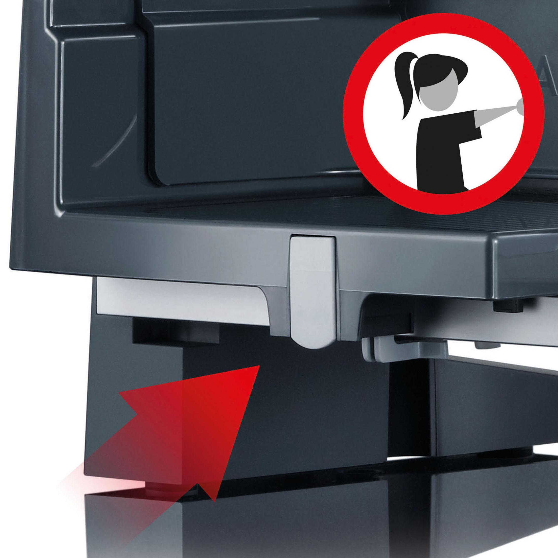 Zbliżenie na maszynę z znakiem ostrzegawczym: nie dotykać. Czerwona strzałka wskazuje podstawę.