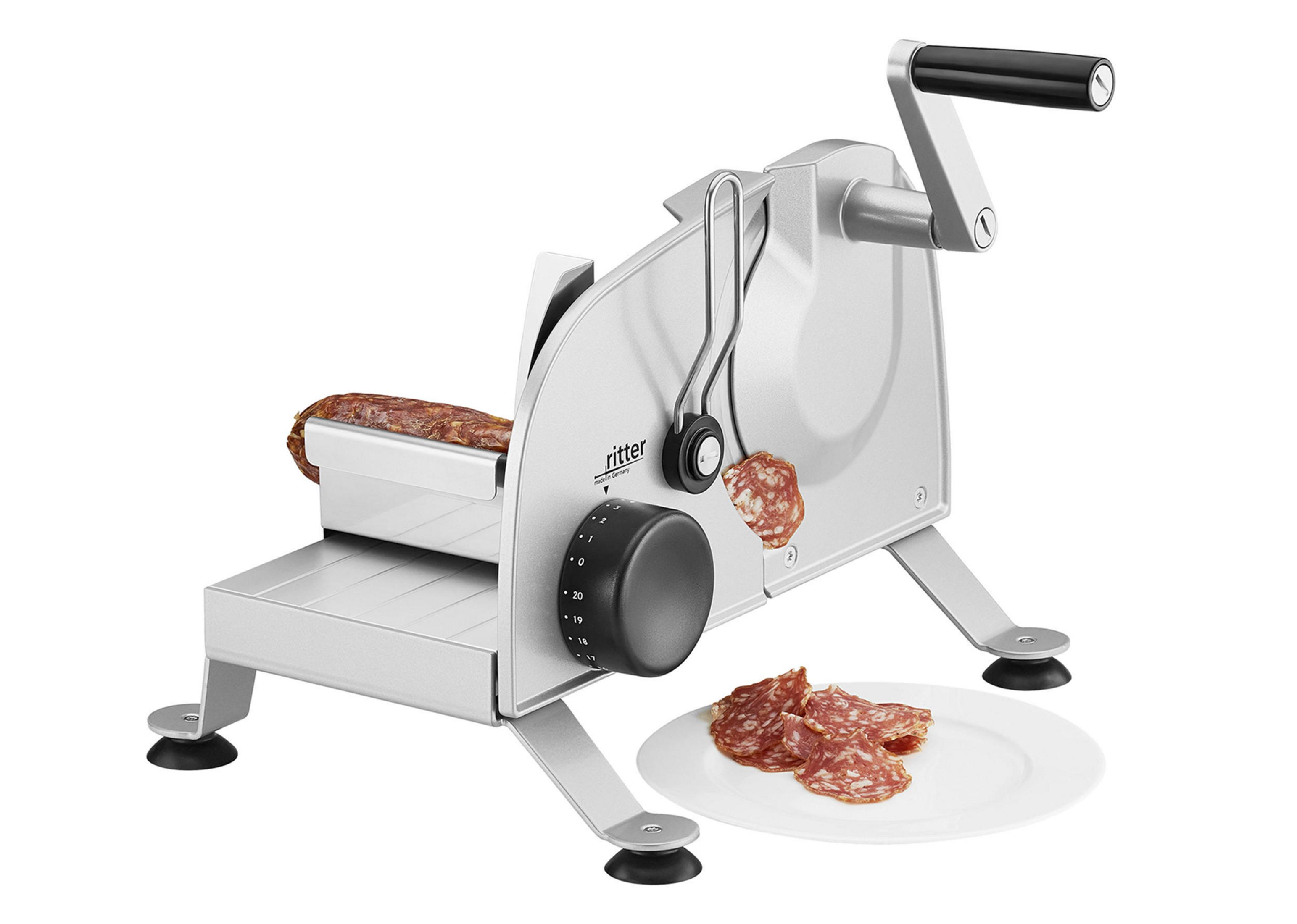 Krajalnica do kiełbasy z salami. Pokrojone salami na talerzu. Maszyna jest srebrna.