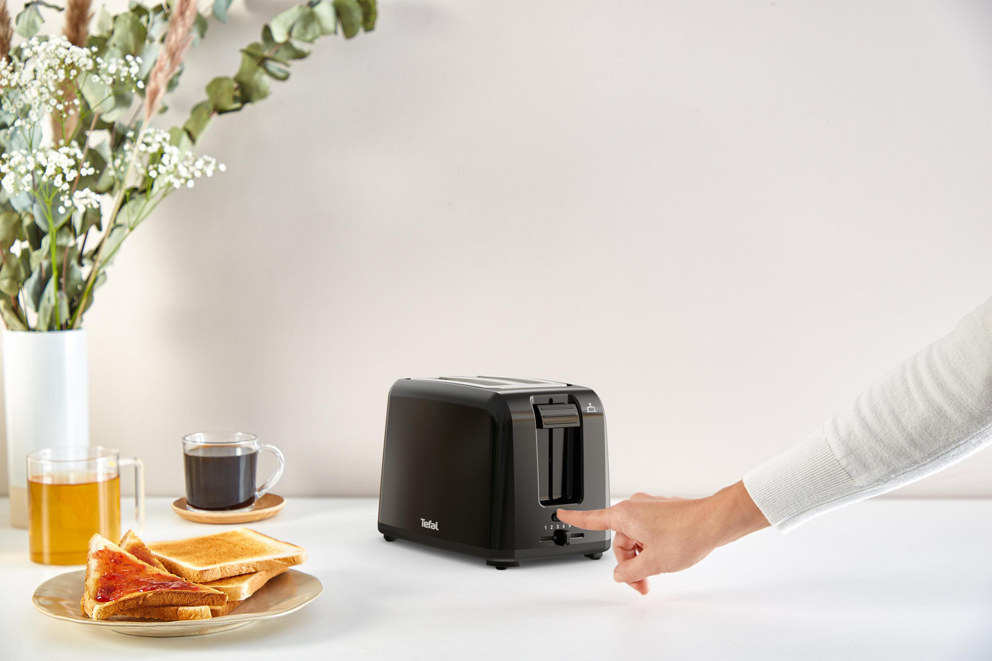 Hand einer Person, die einen Knopf an einem schwarzen Toaster drückt.